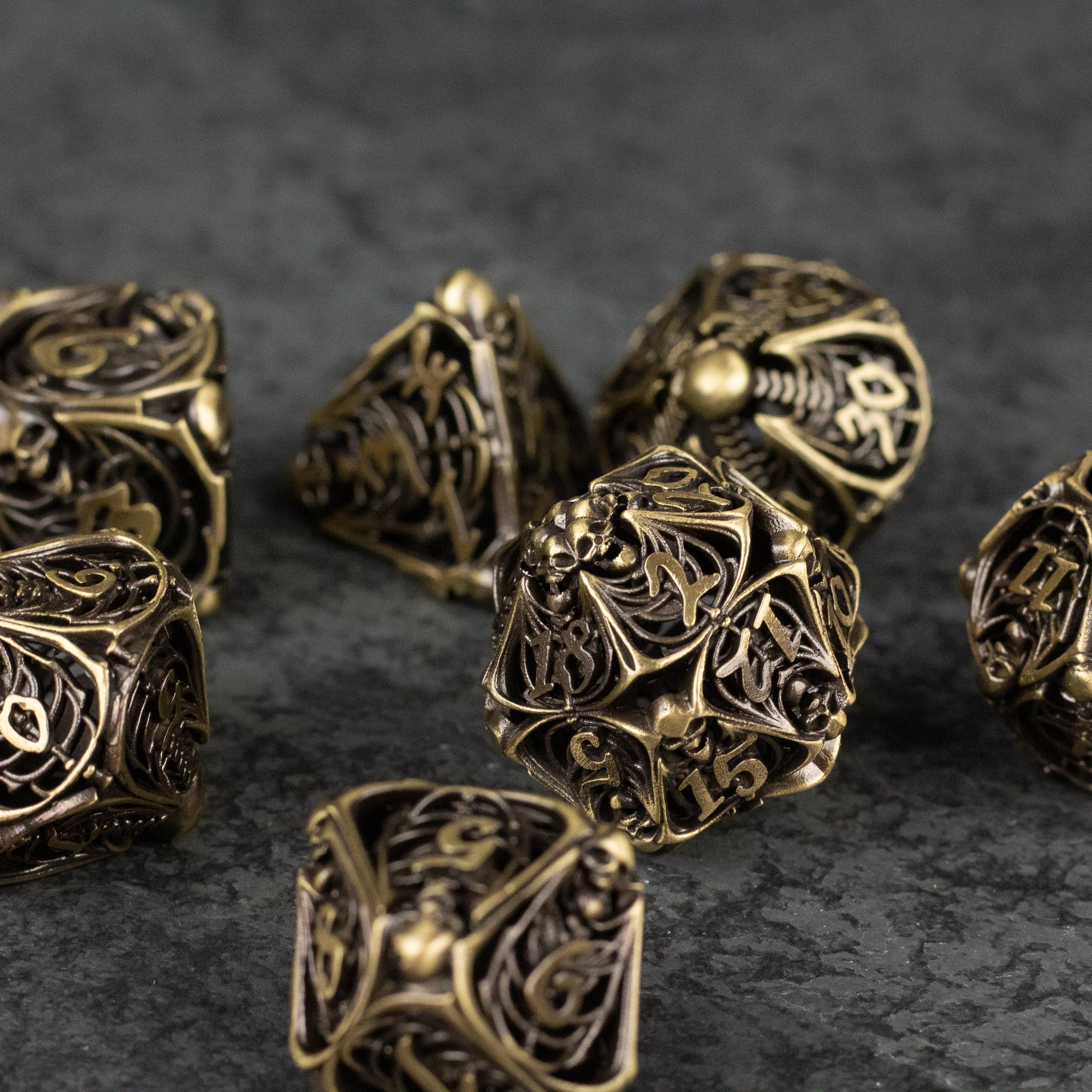 Bone Crypt Dice Set - Antique gold-toned metal dice set with intricate necromancer-inspired filigree and hollow designs.
