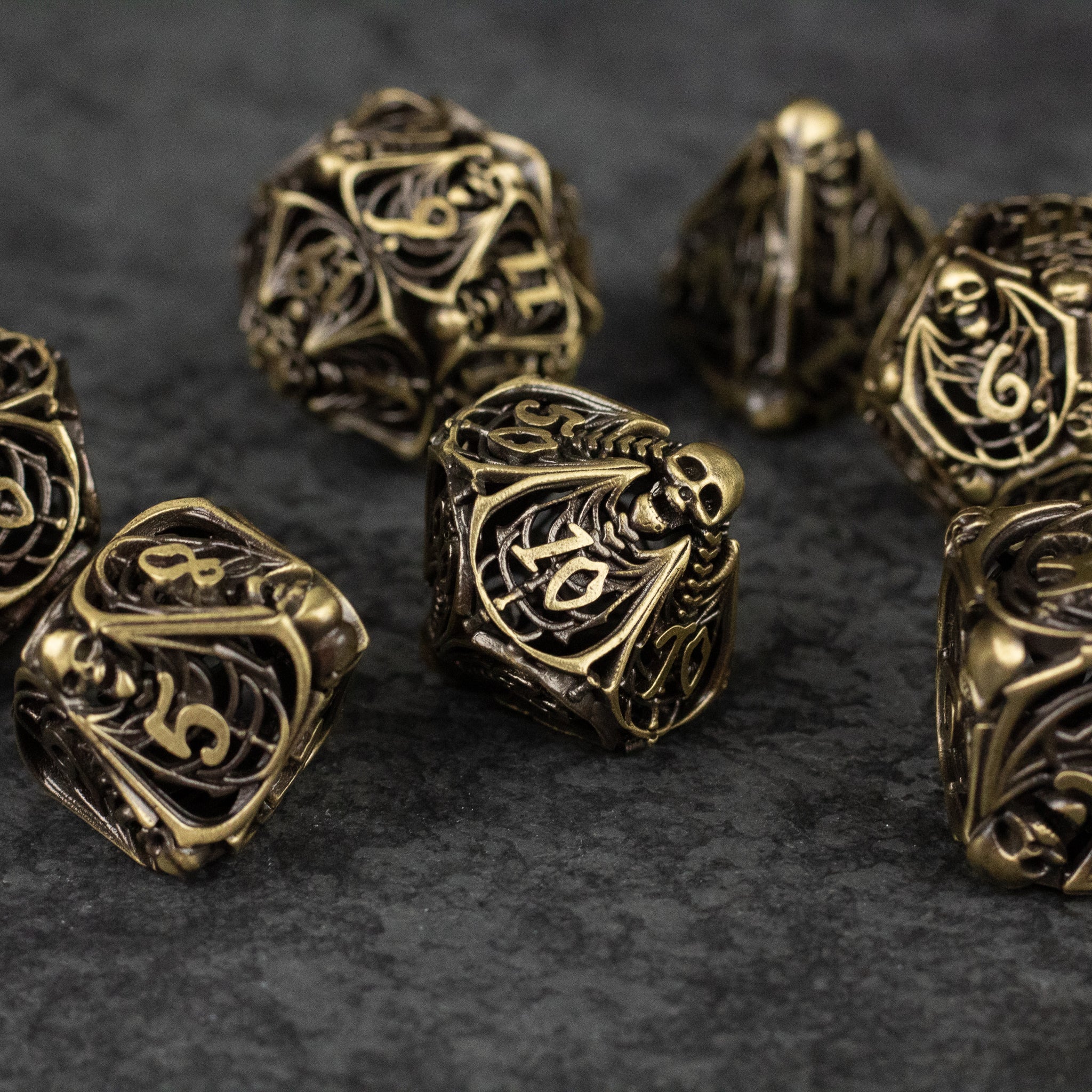 Bone Crypt Dice Set - Black and gold hollow metal dice set with intricate bone-inspired engraving and necromancer theme.