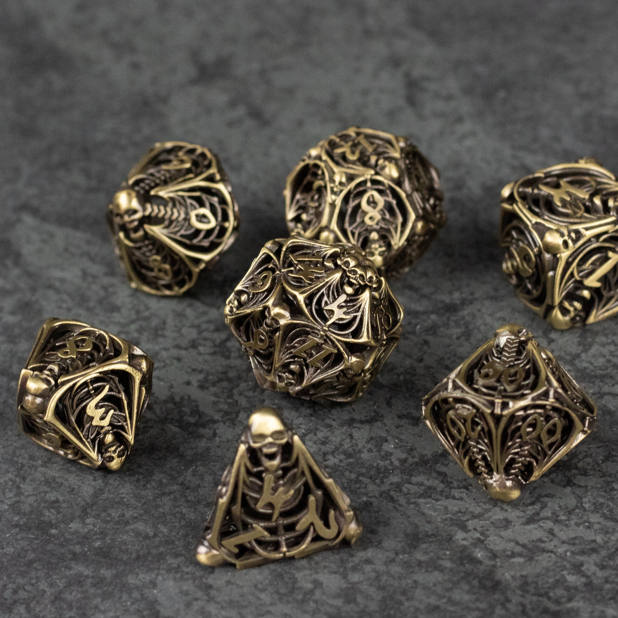 Bone Crypt Dice Set - Metallic gold hollow dice set with intricate bone and skeleton designs, various polyhedral shapes.