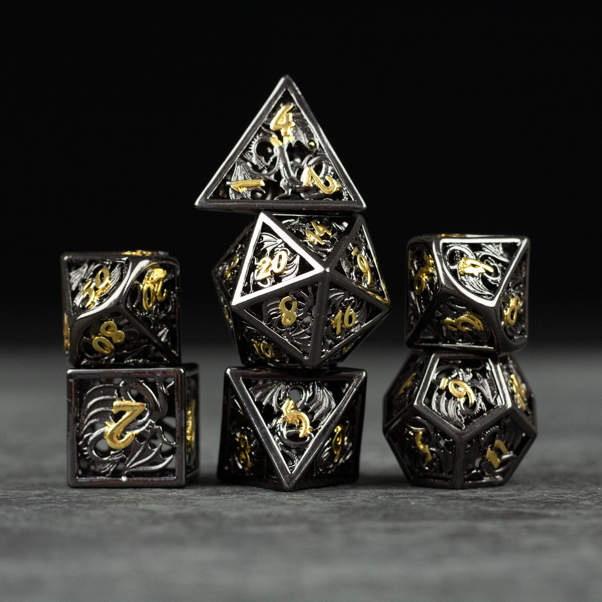 Black and Gold Dragon Hollow Dice Set - Black and gold hollow metal polyhedral dice set with dragon designs on dark background.