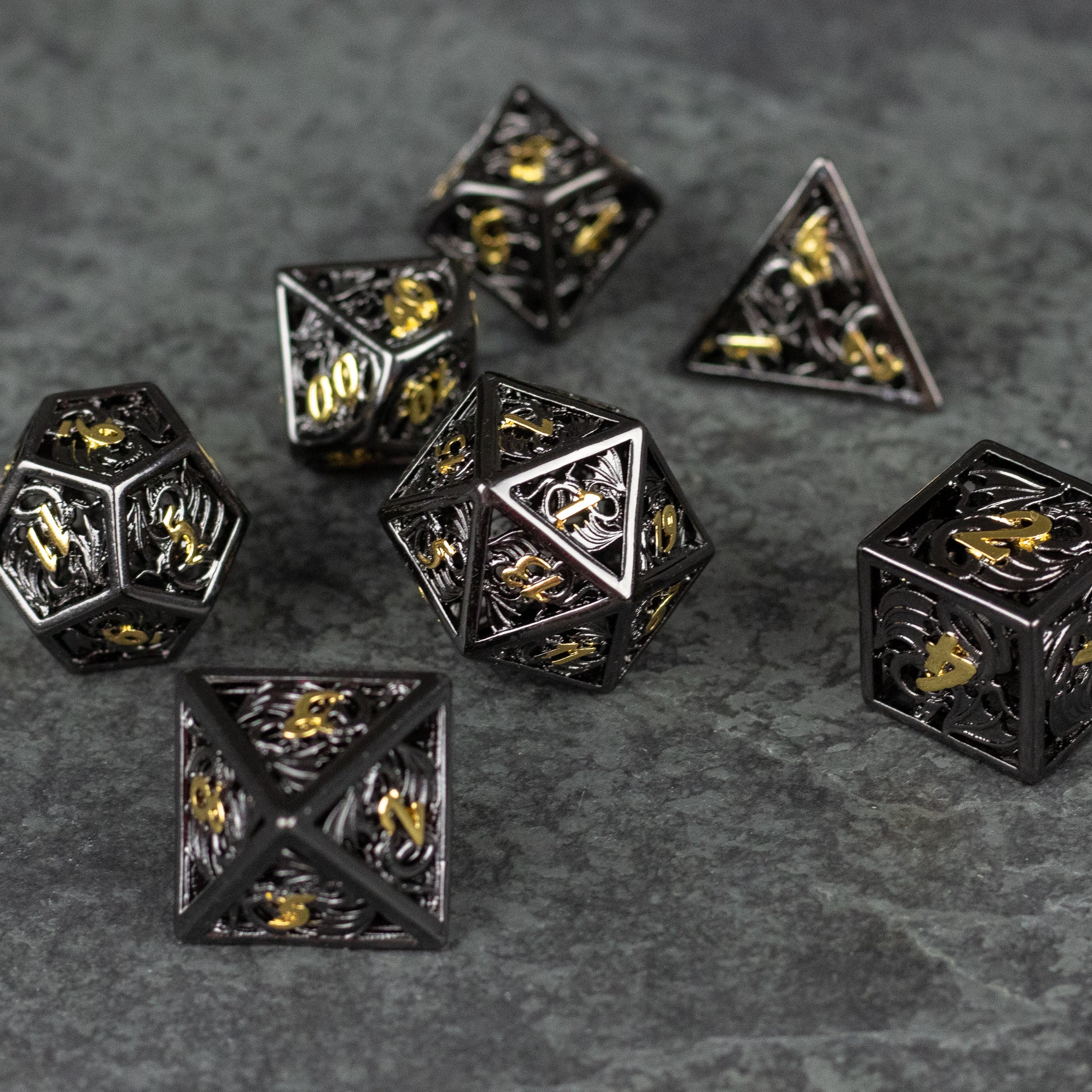 Black and Gold Dragon Hollow Dice Set - Black hollow metal dice set with intricate gold dragon designs on each face.