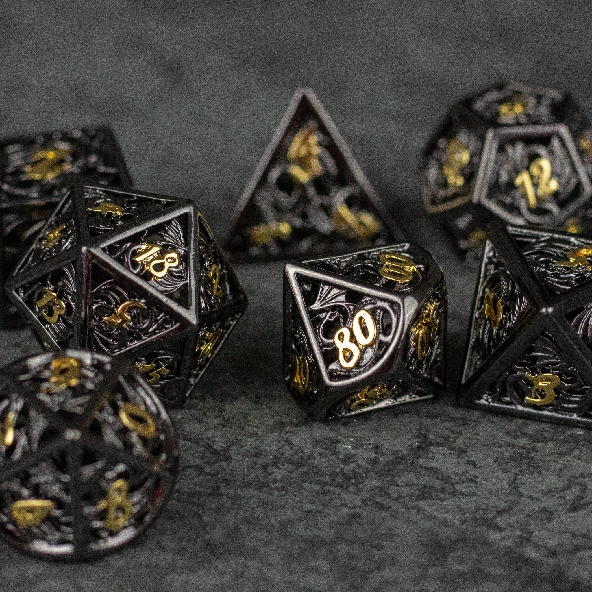 Black and Gold Dragon Hollow Dice Set - Black hollow metal dice set with gold numbering and intricate dragon designs.