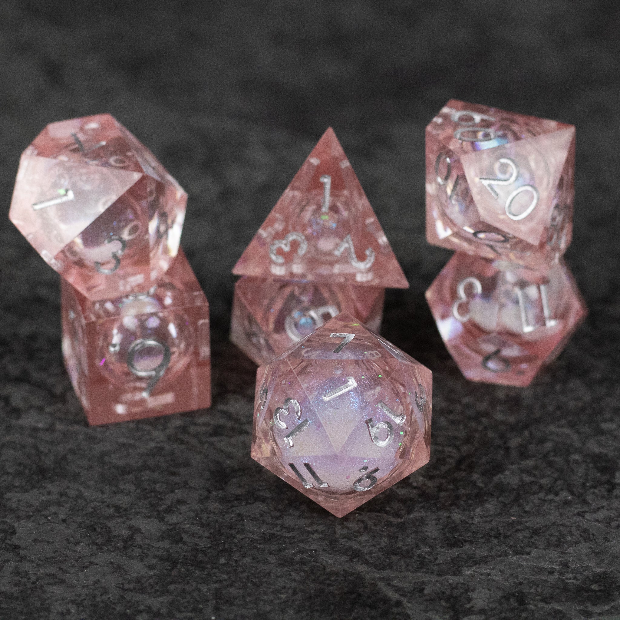 Fairy Dust - Liquid Core Dice Set - Set of seven translucent pink sharp-edged polyhedral dice with liquid core and white numbers.