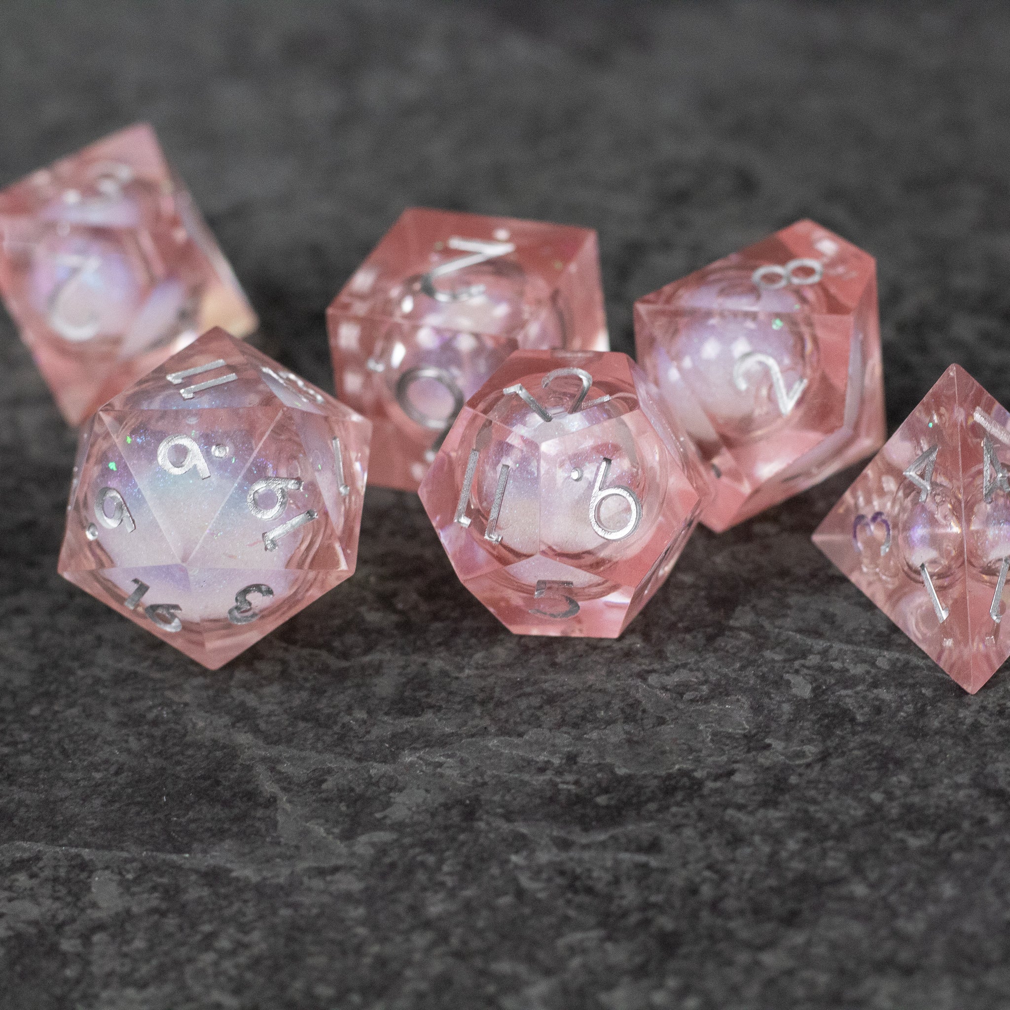Fairy Dust - Liquid Core Dice Set - Set of seven pink translucent polyhedral dice with sharp edges and swirling liquid core, white numbering.