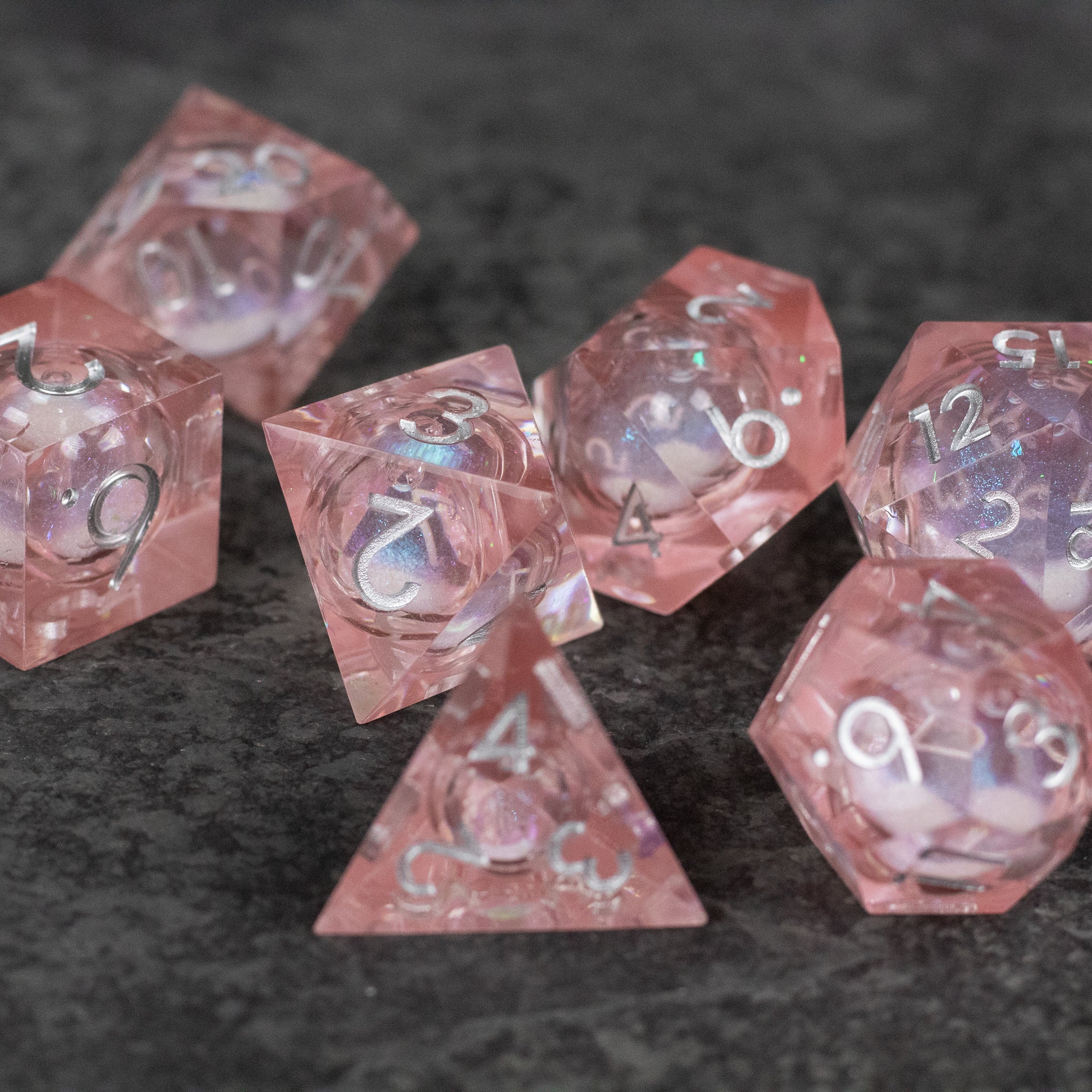 Fairy Dust - Liquid Core Dice Set - Set of translucent pink polyhedral dice with sharp edges and white numbering, featuring a liquid core effect.