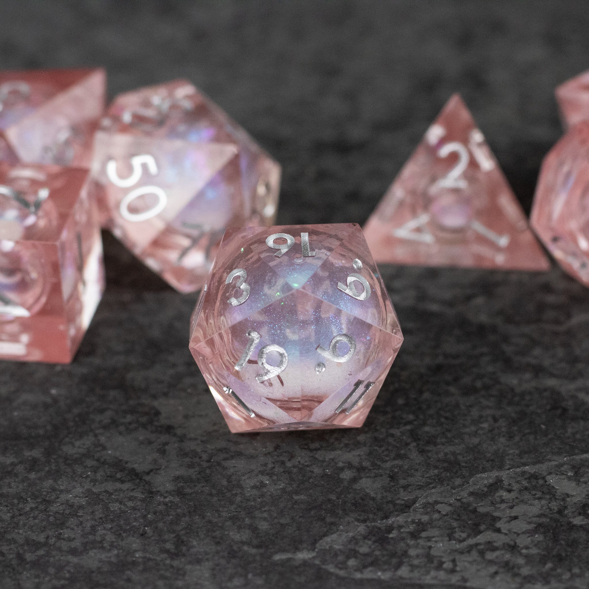 Fairy Dust - Liquid Core Dice Set - Set of translucent pink sharp-edged polyhedral dice with a shimmering liquid core and white numbering.