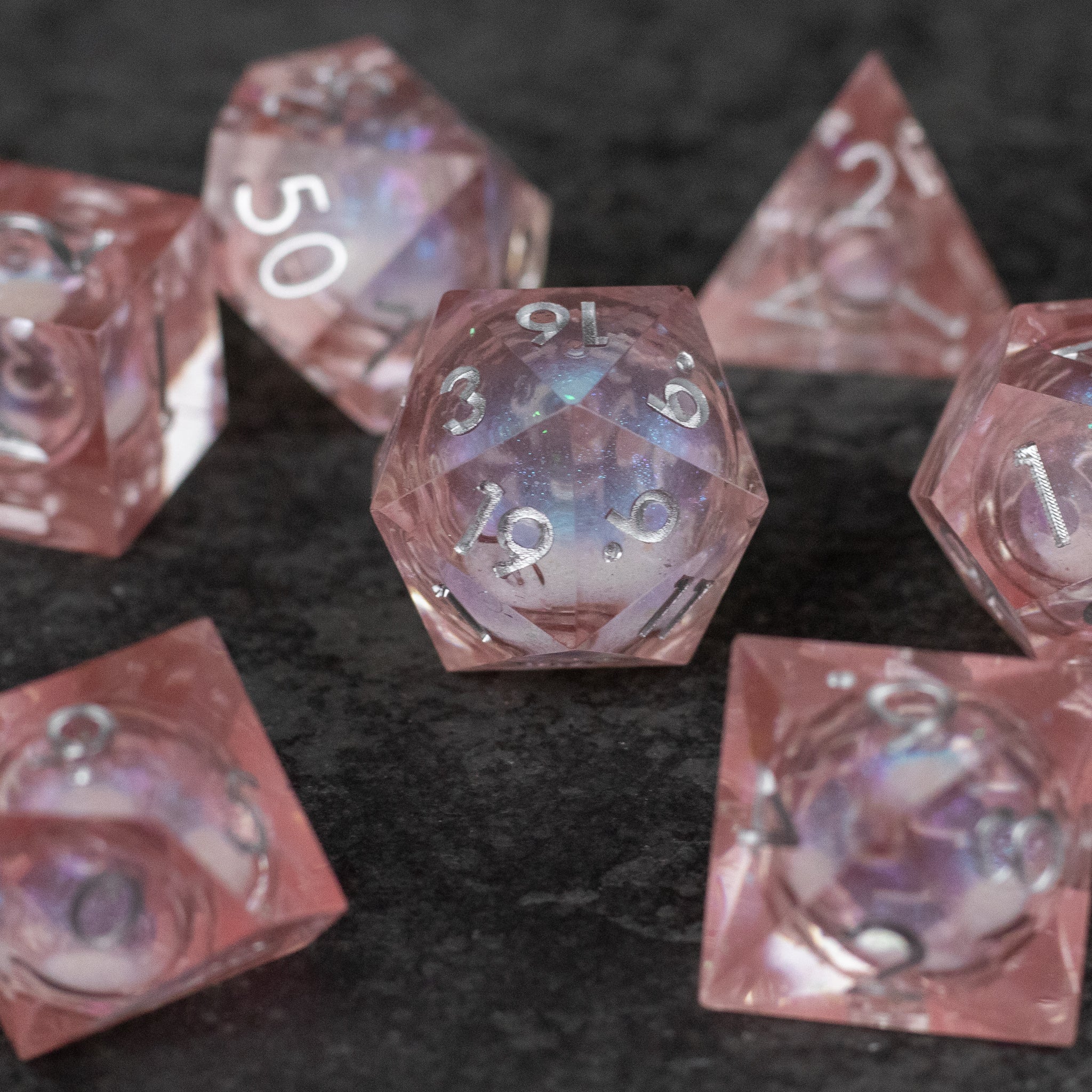 Fairy Dust - Liquid Core Dice Set - Set of translucent pink sharp-edged polyhedral dice with liquid core and white numbering.
