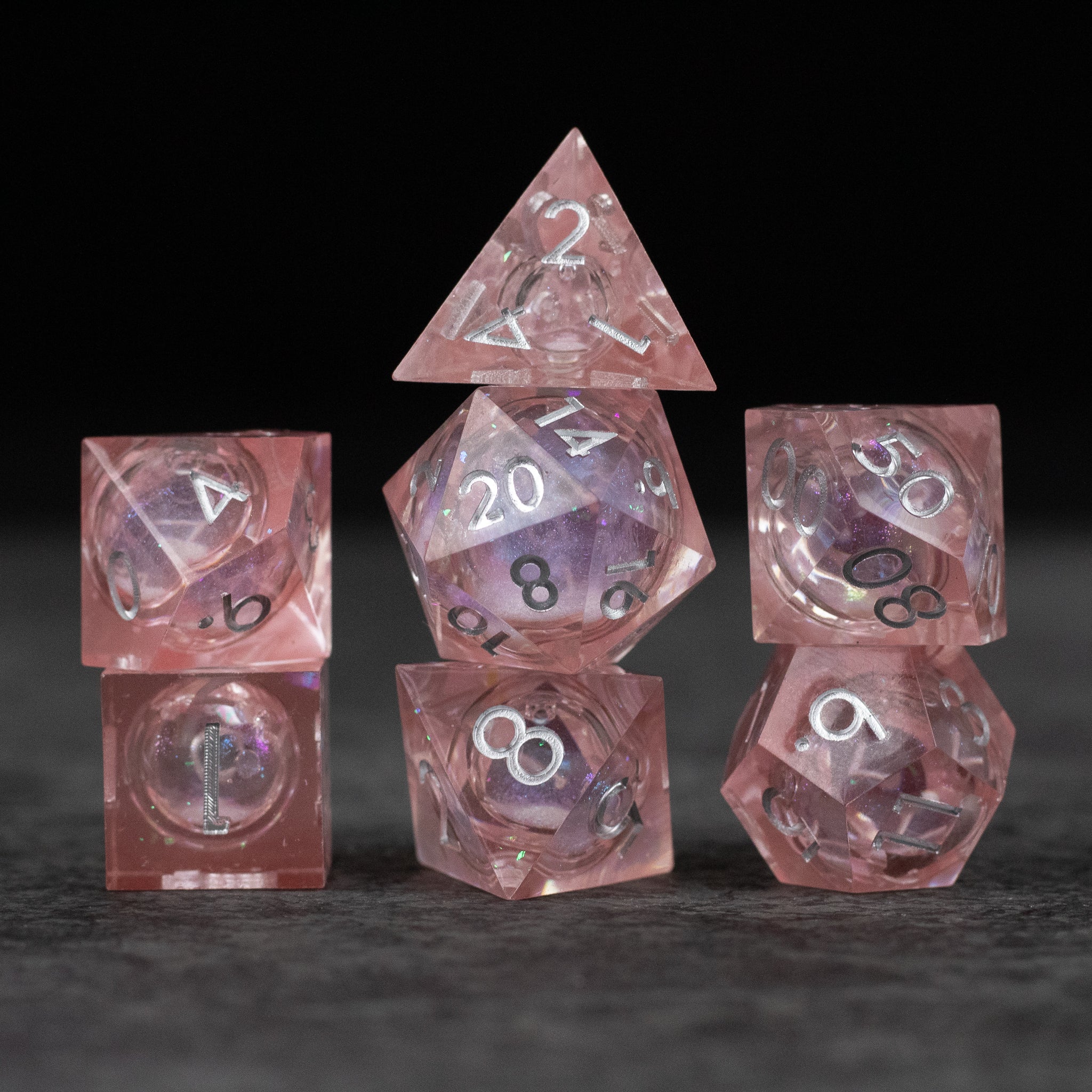 Fairy Dust - Liquid Core Dice Set - Set of seven pink translucent sharp-edged dice with liquid core and white numbering.