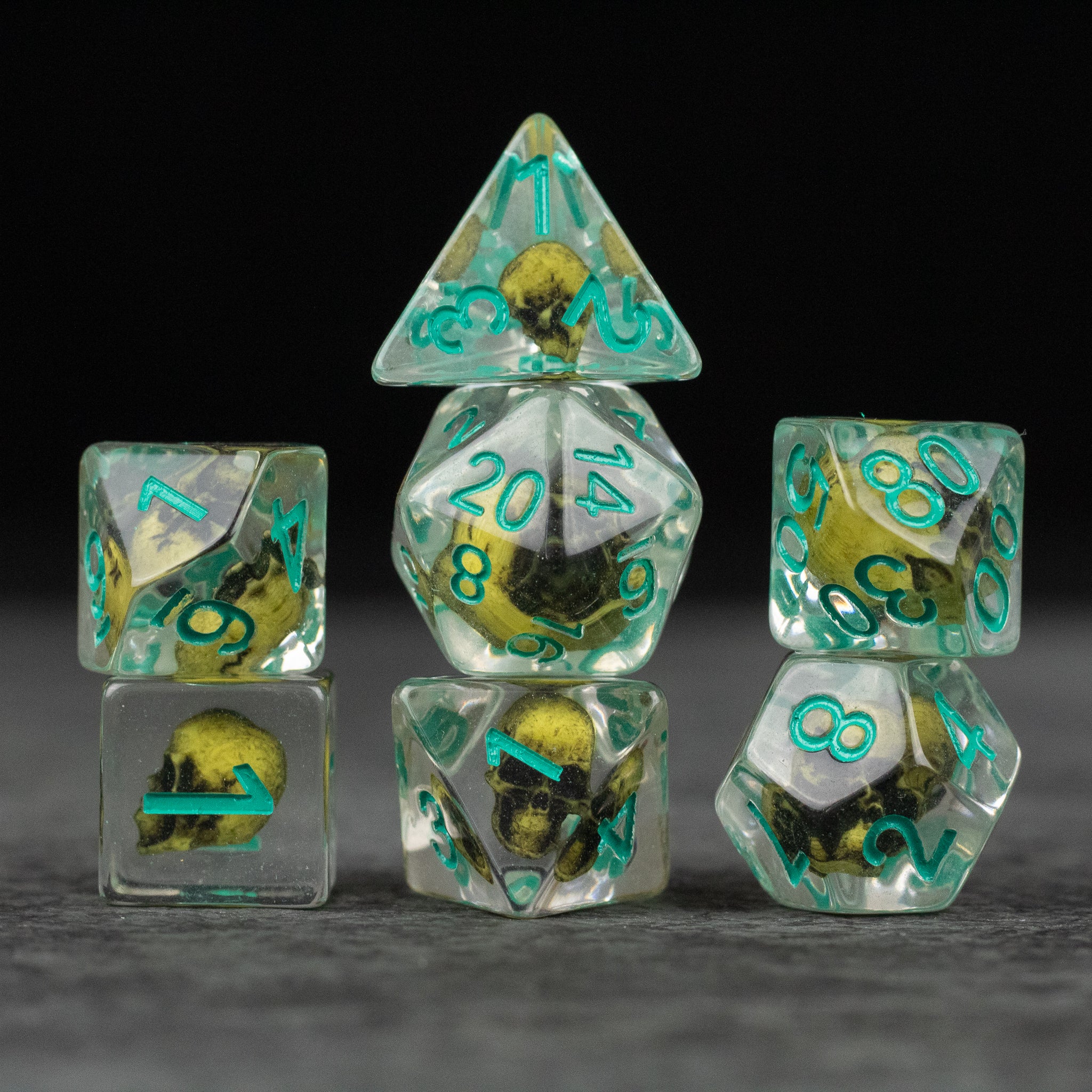 Yellow Skull Dice Set - Transparent dice set with embedded yellow skulls and teal numbers, including d4, d6, d8, d10, d12, and d20 shapes.
