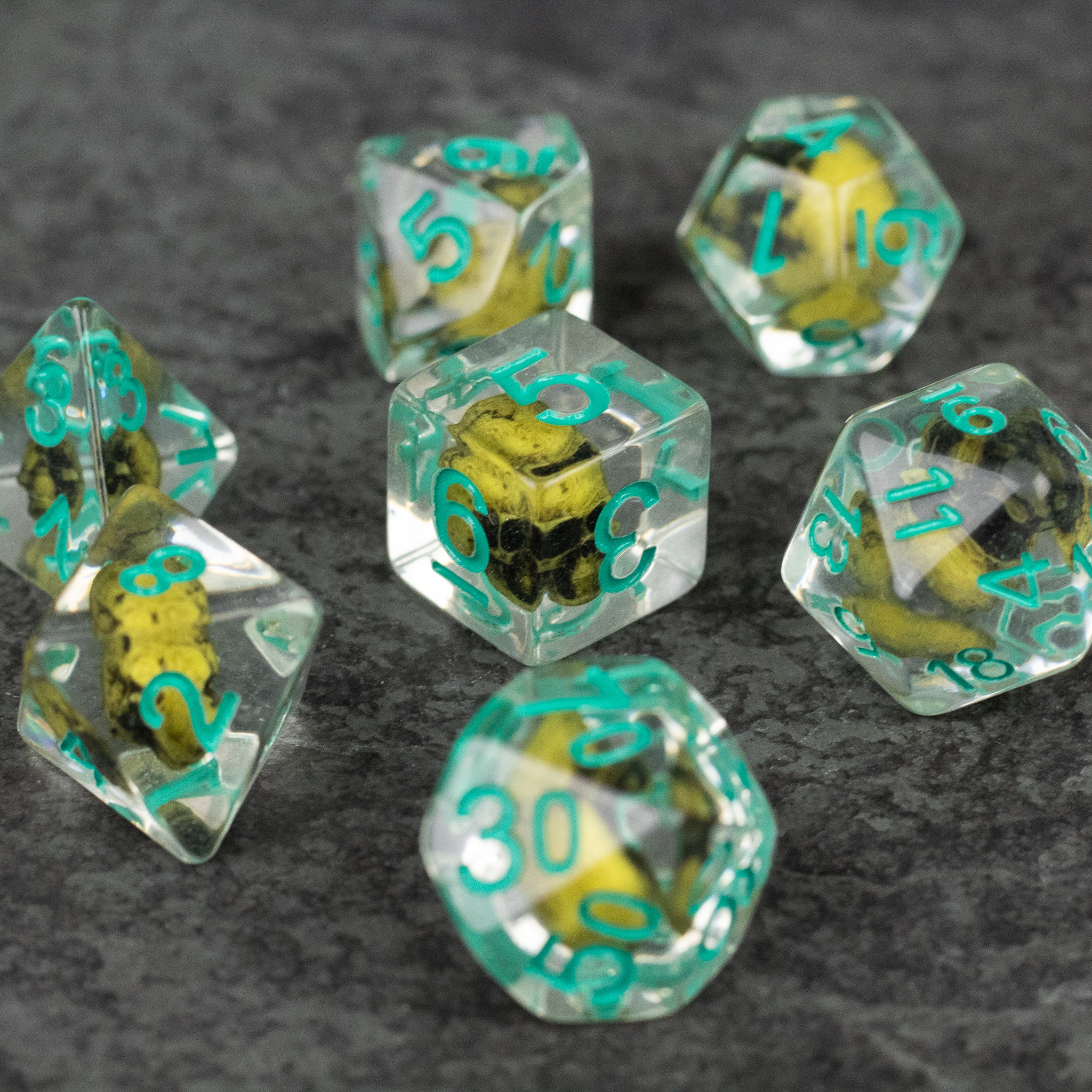 Yellow Skull Dice Set - Clear polyhedral dice set with yellow skulls inside and teal numbers, including d20, d12, d10, d8, d6, and d4.