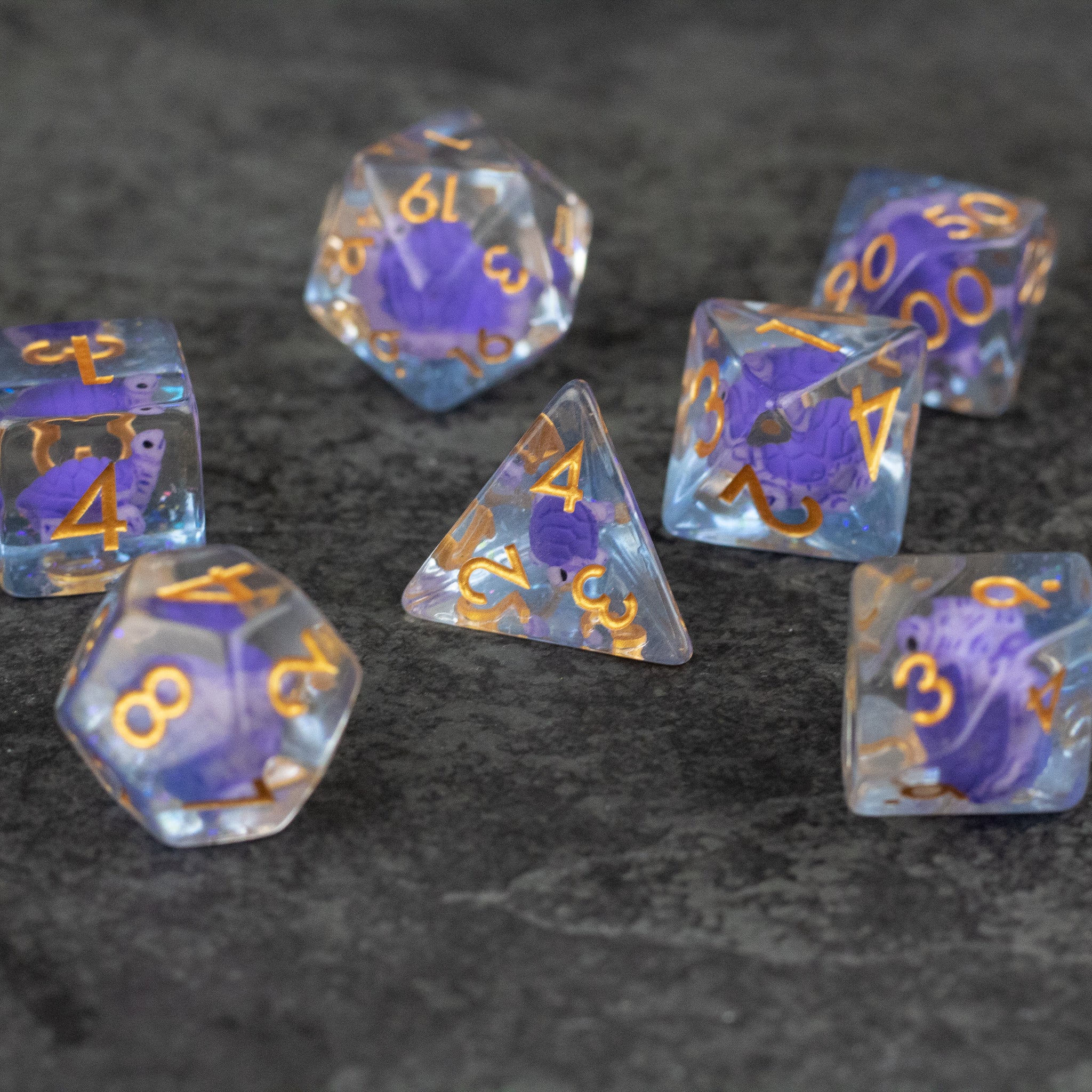 Purple Turtle Dice Set - Translucent purple and clear polyhedral dice set with gold numbering, featuring a swirled turtle design inside each die.