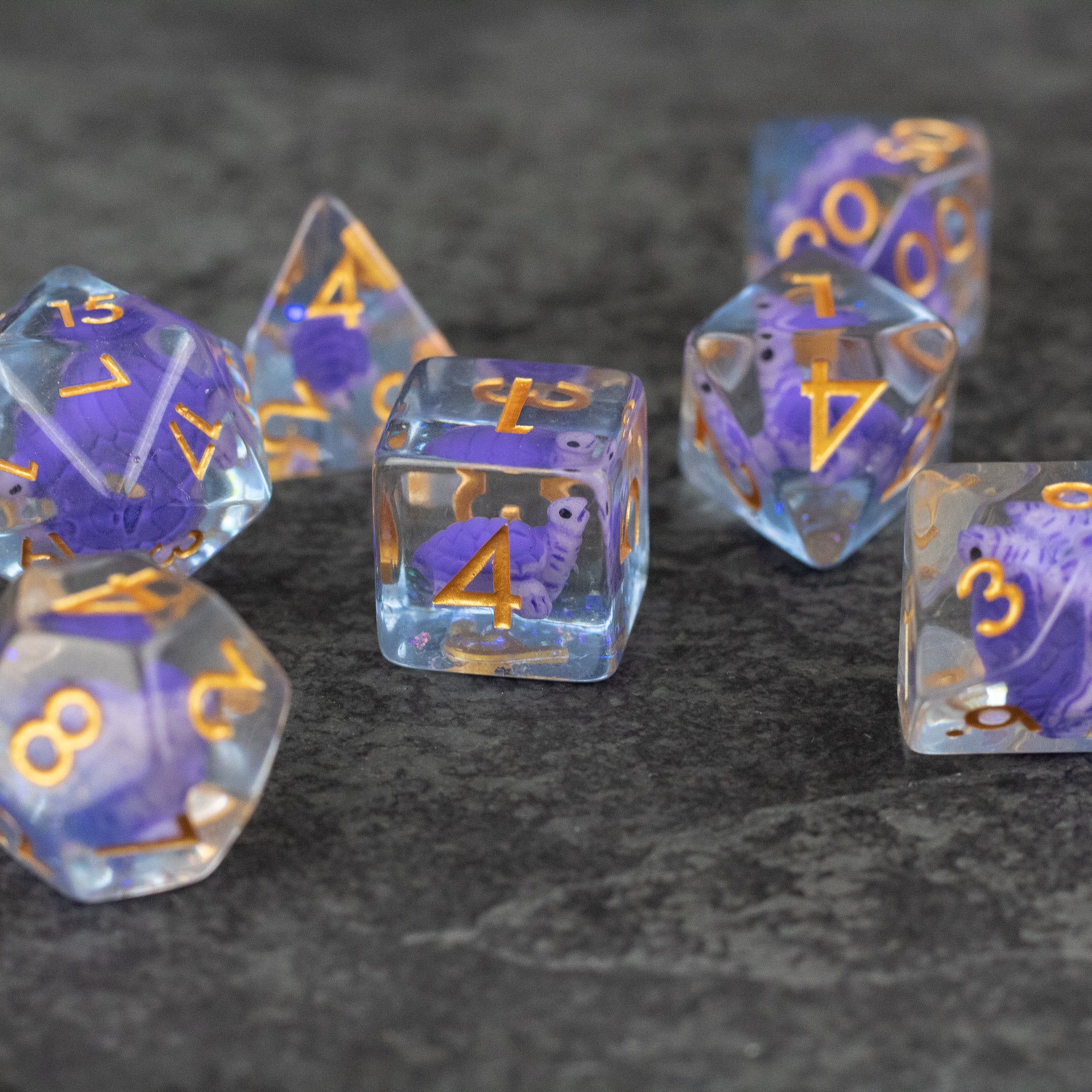 Purple Turtle Dice Set - Set of seven transparent purple polyhedral dice with gold numbers, featuring a small turtle inside each die.