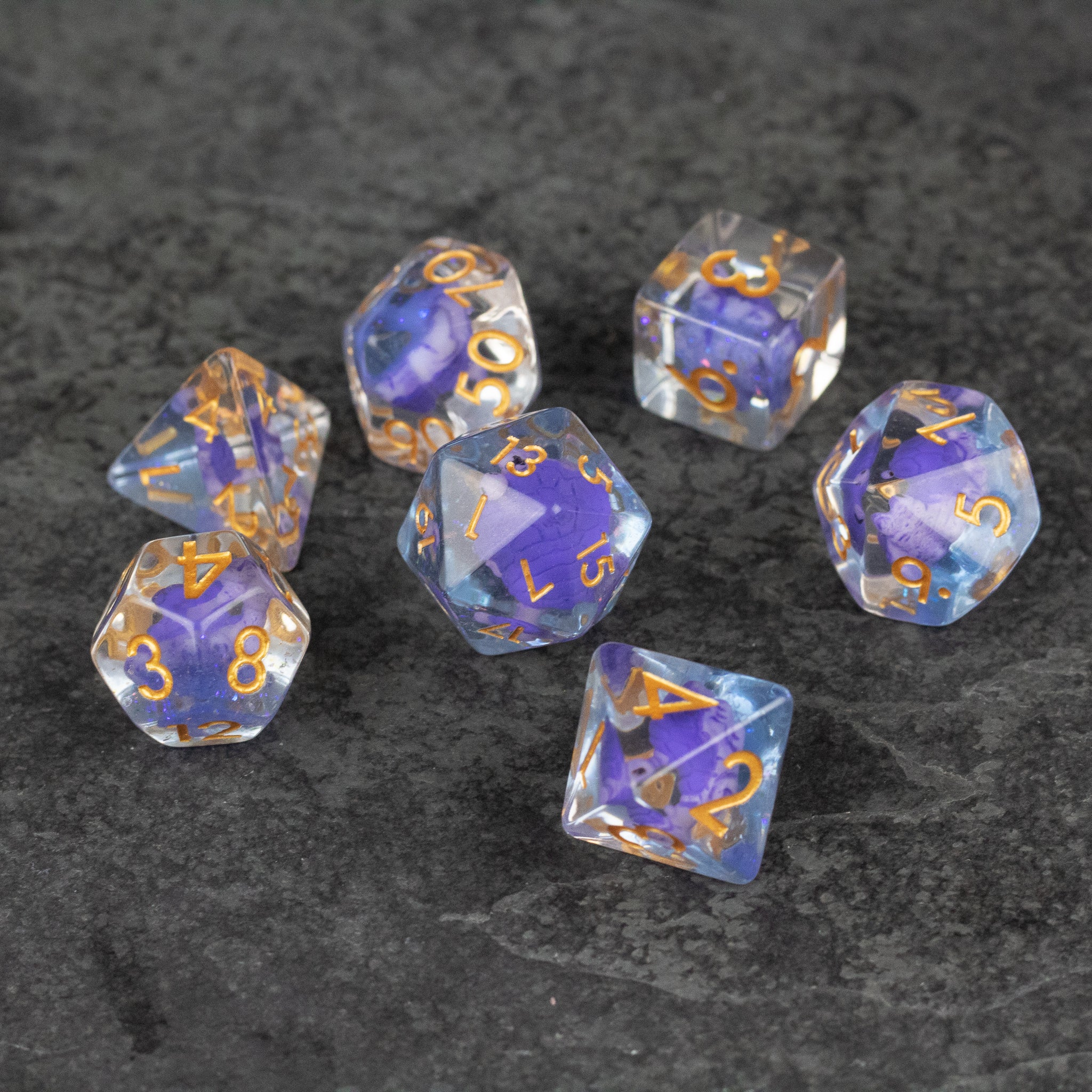 Purple Turtle Dice Set - Set of seven translucent purple polyhedral dice with gold numbers on a dark textured surface.