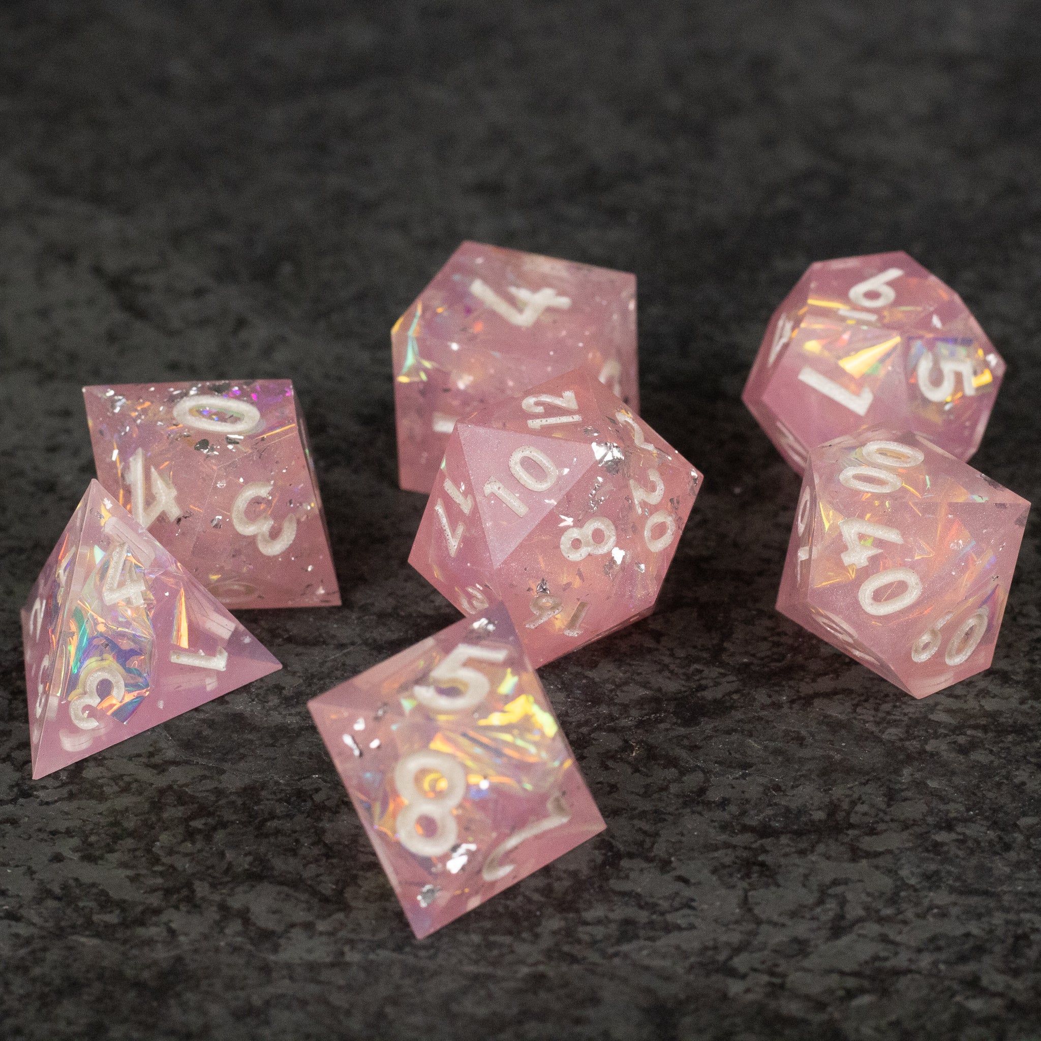 Bubblegum Dice Set - Set of seven translucent pink polyhedral dice with sharp edges and white numbers, including d4, d6, d8, d10, d12, and d20.