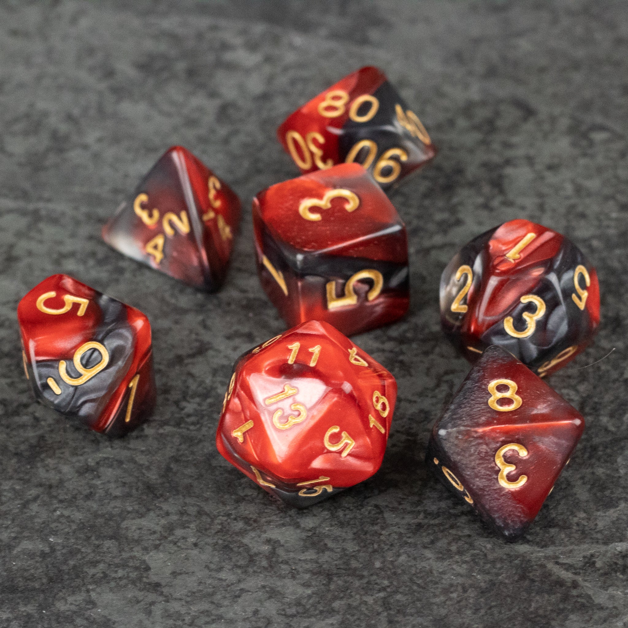 Red and Black Marbled Dice Set - Set of seven acrylic dice with red and black marbled patterns and gold numbering.