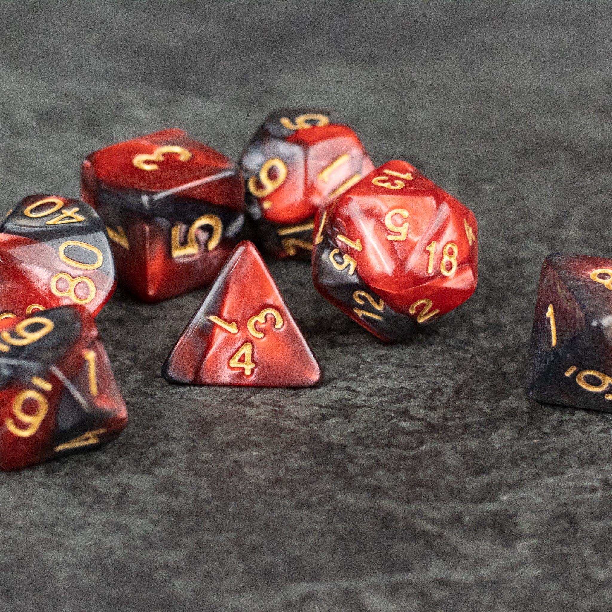 Red and Black Marbled Dice Set - Set of red and black marbled acrylic dice with gold numbering, including various polyhedral shapes.