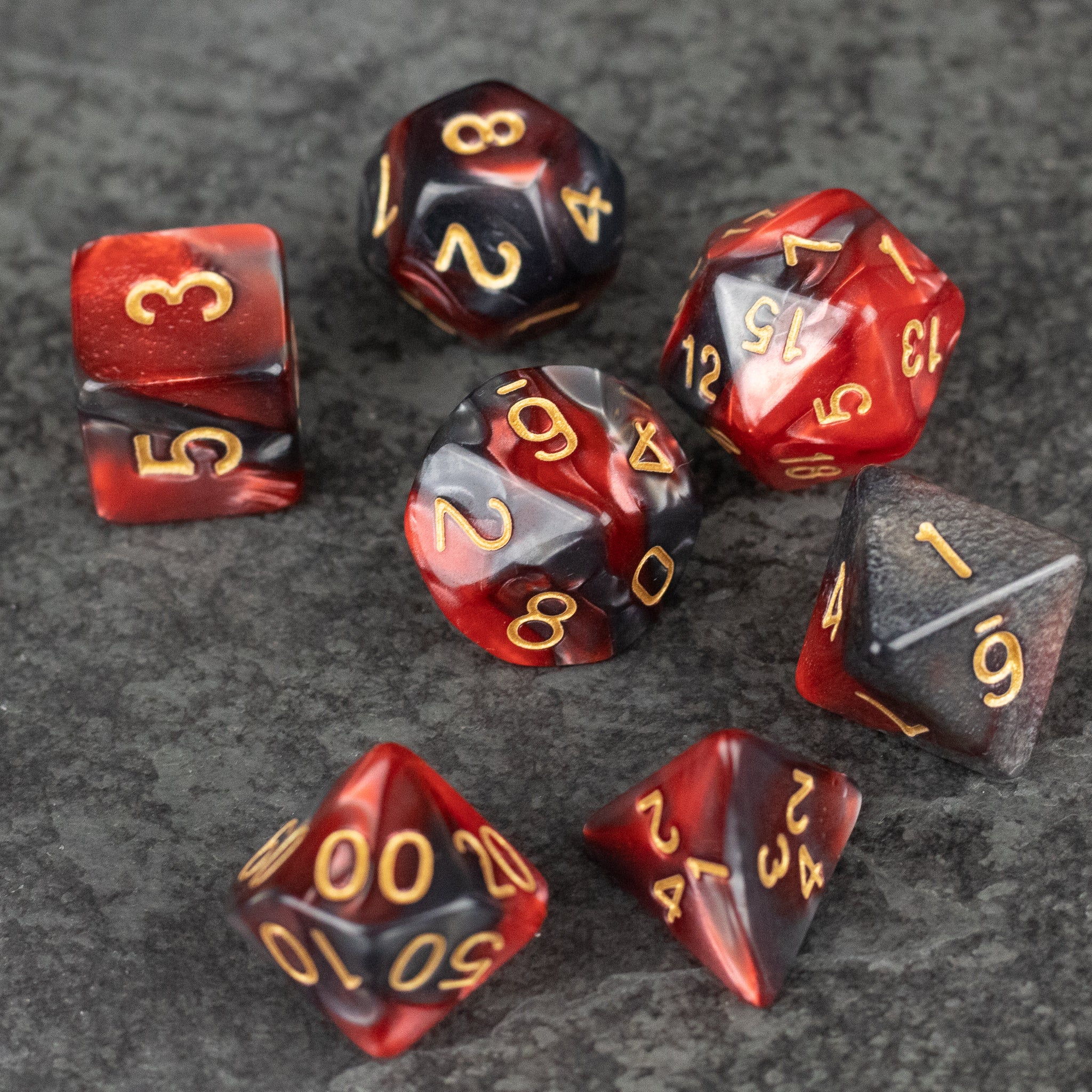 Red and Black Marbled Dice Set - Seven red and black marbled acrylic dice with gold numbering, featuring various shapes including d20, d12, d10, d8, d6, and.