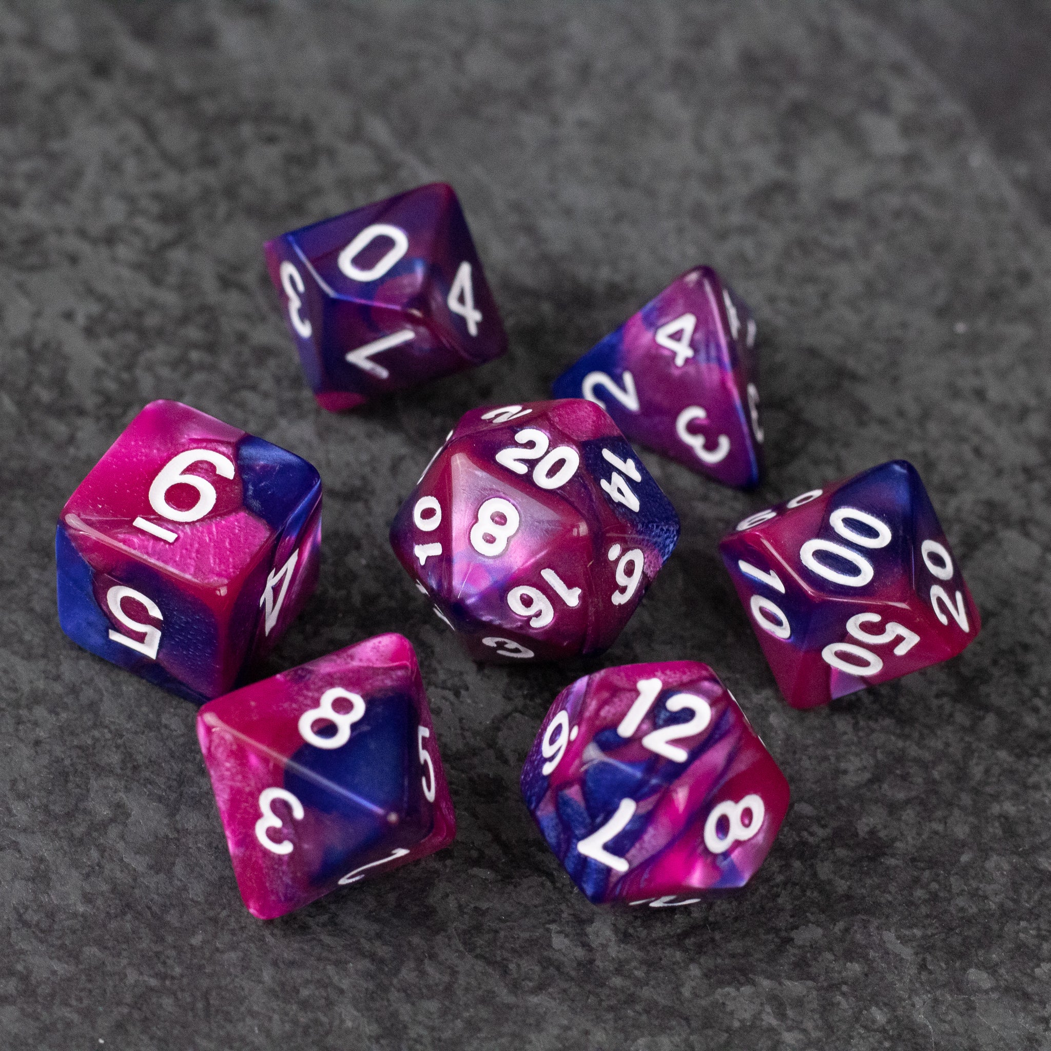 Pink and Blue Marbled Dice Set - Set of seven pink and blue marbled acrylic dice with white numbers on gray background.