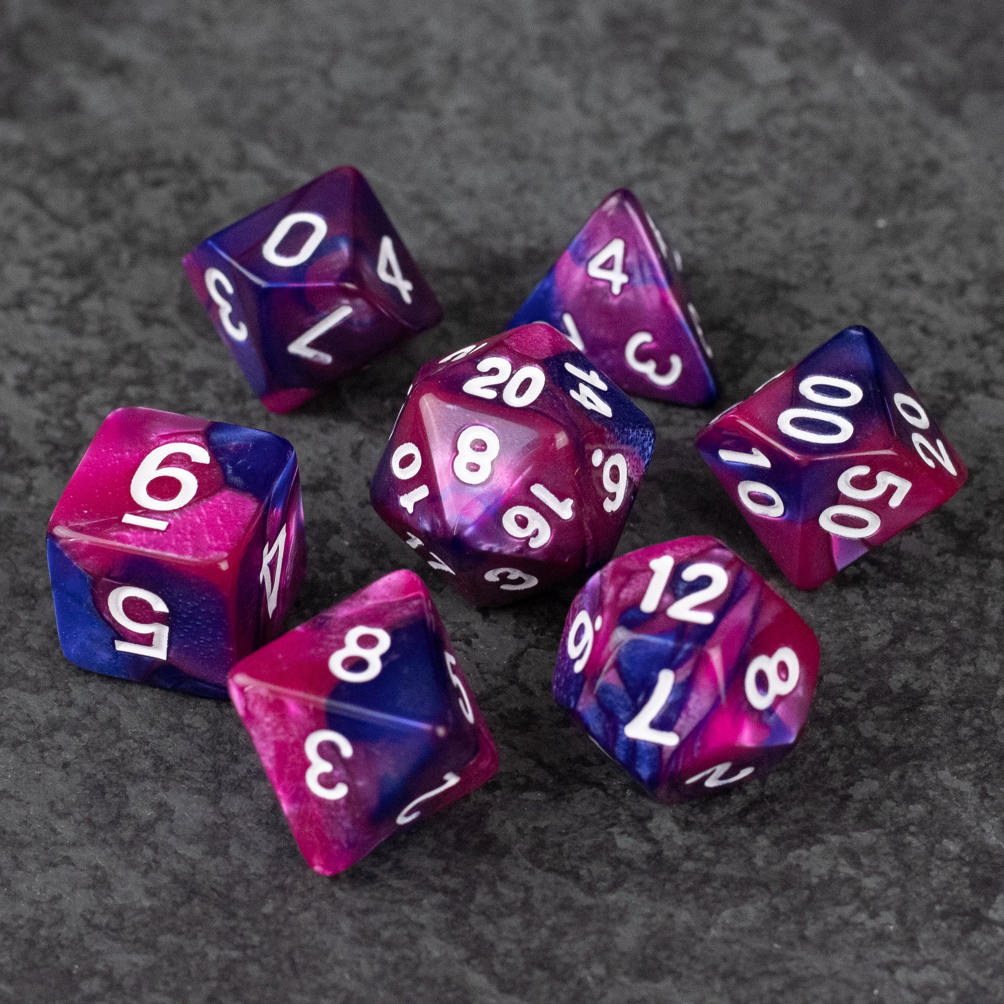 Pink and Blue Marbled Dice Set - Pink and blue marbled acrylic dice set with white numbers on a gray surface.