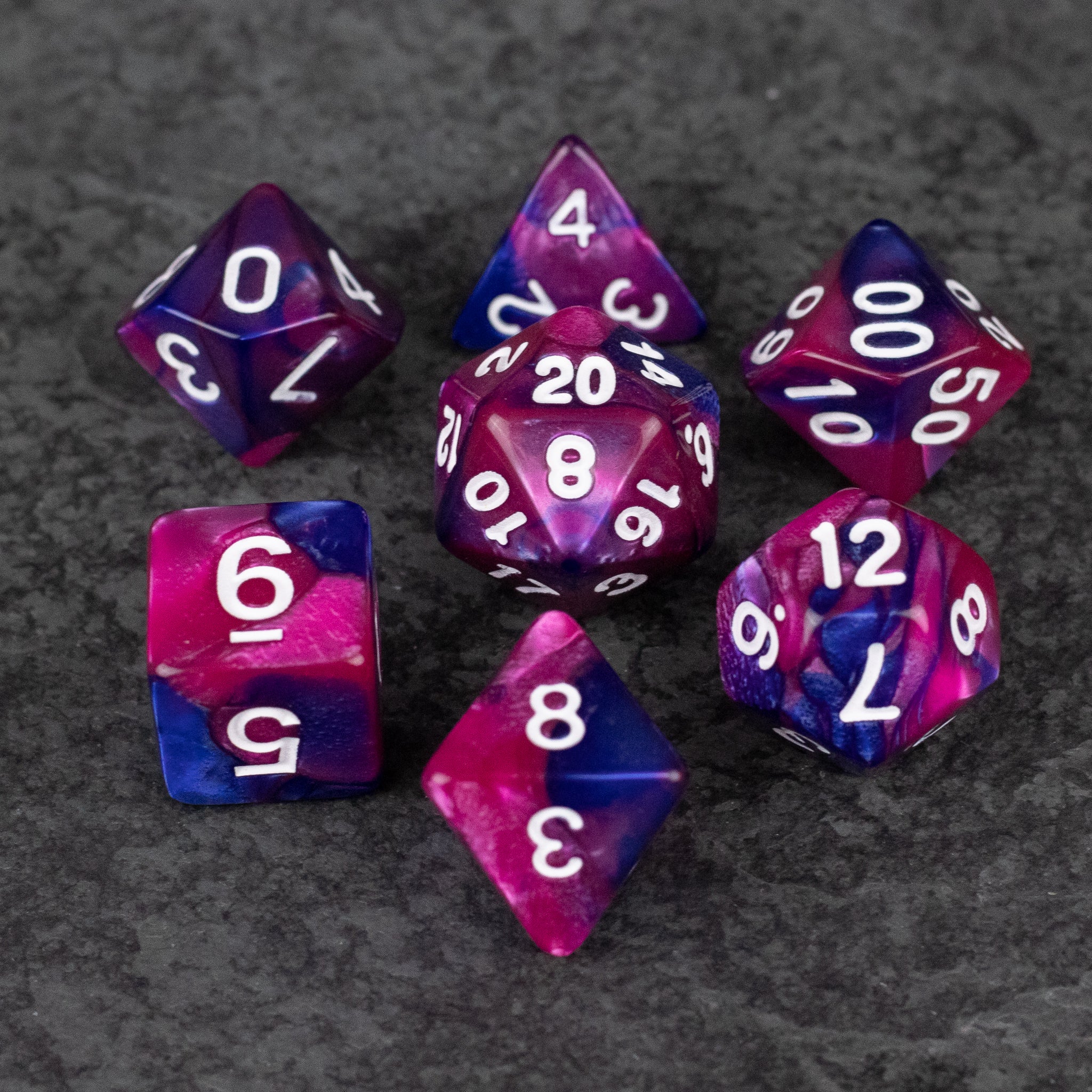 Pink and Blue Marbled Dice Set - Set of seven pink and blue marbled acrylic dice with white numbers on dark gray background.