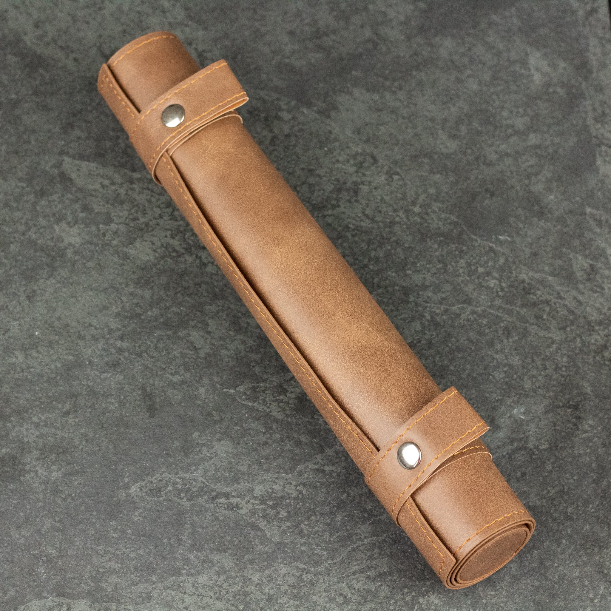Scroll Dice Mat - Rolled brown leather scroll dice mat with snap button straps on gray surface.