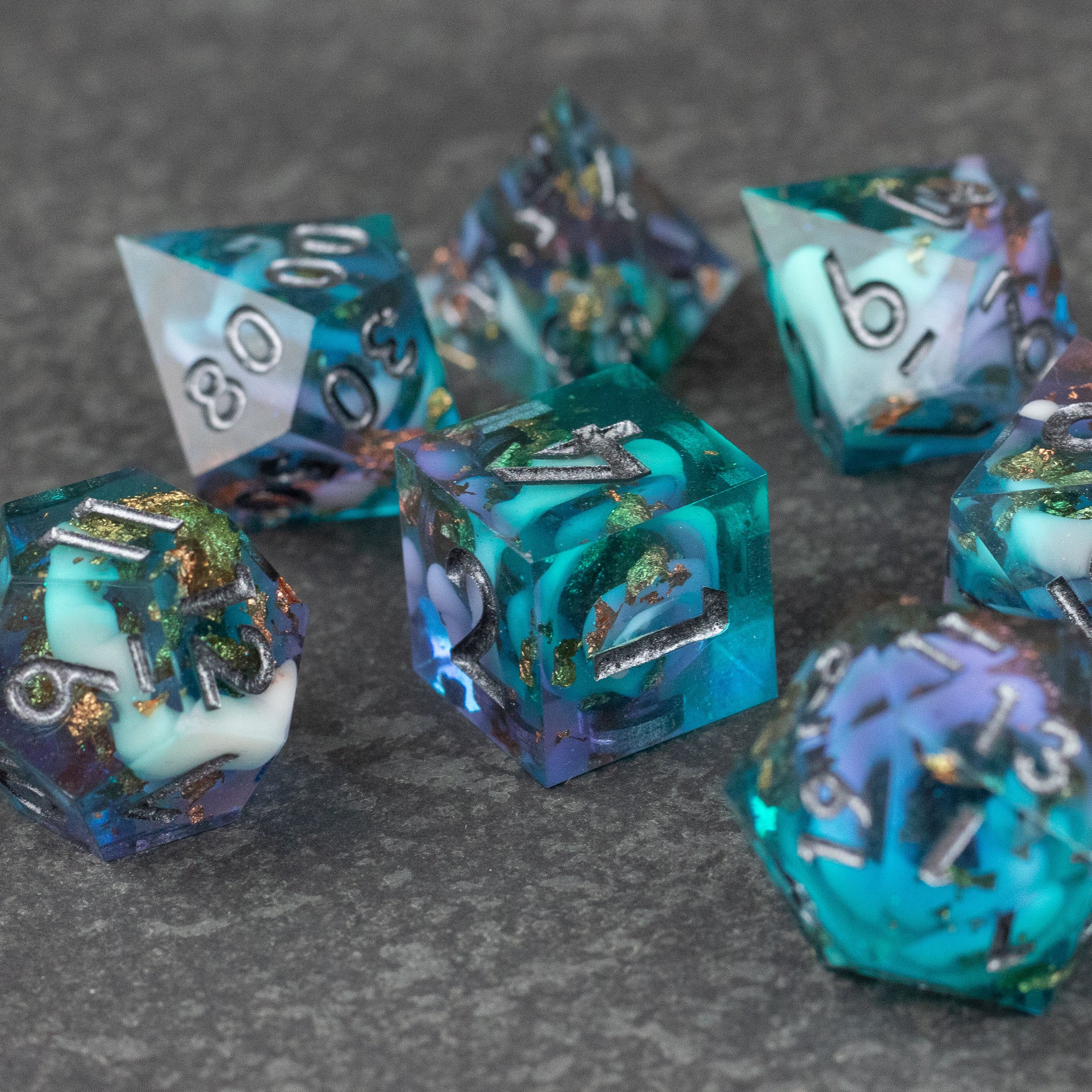 Frostfall Dice Set - Set of translucent polyhedral dice in shades of teal, purple, and white with silver numbers and sharp edges.