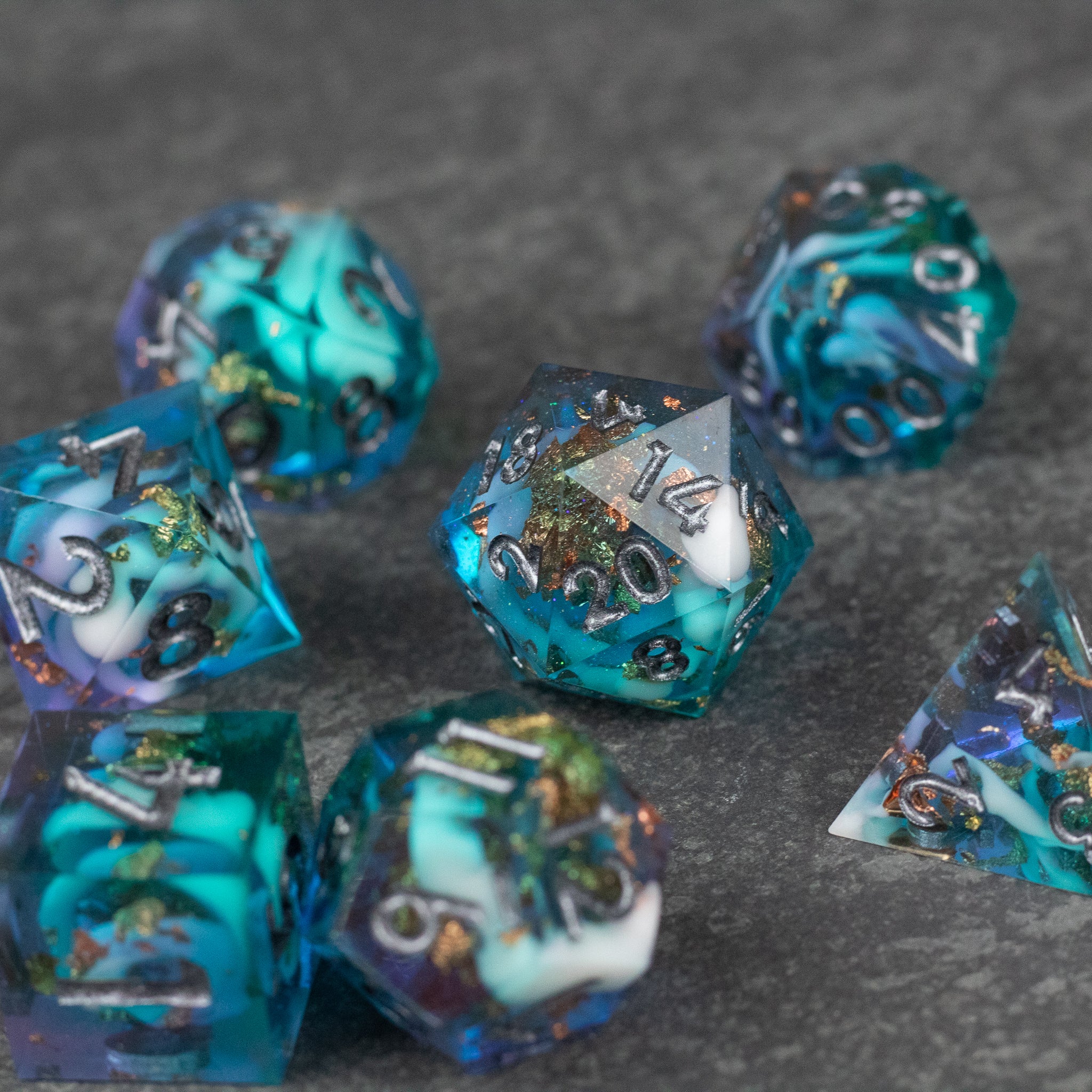 Frostfall Dice Set - Blue and teal translucent sharp-edged polyhedral dice set with metallic silver numbers and flecks inside.