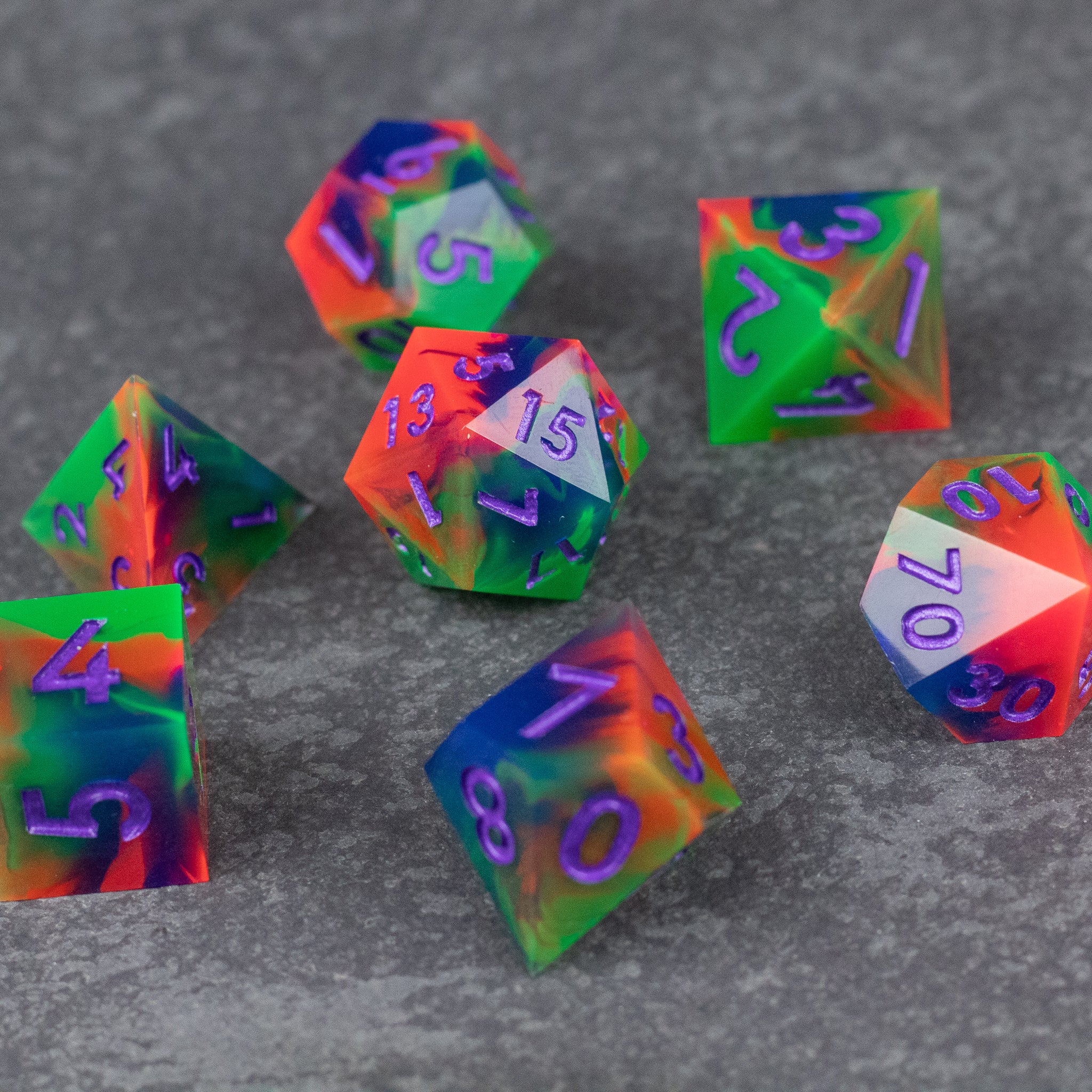 Neon Demon Dice Set - Set of neon green and pink sharp-edged polyhedral dice with purple numbering on a gray surface.