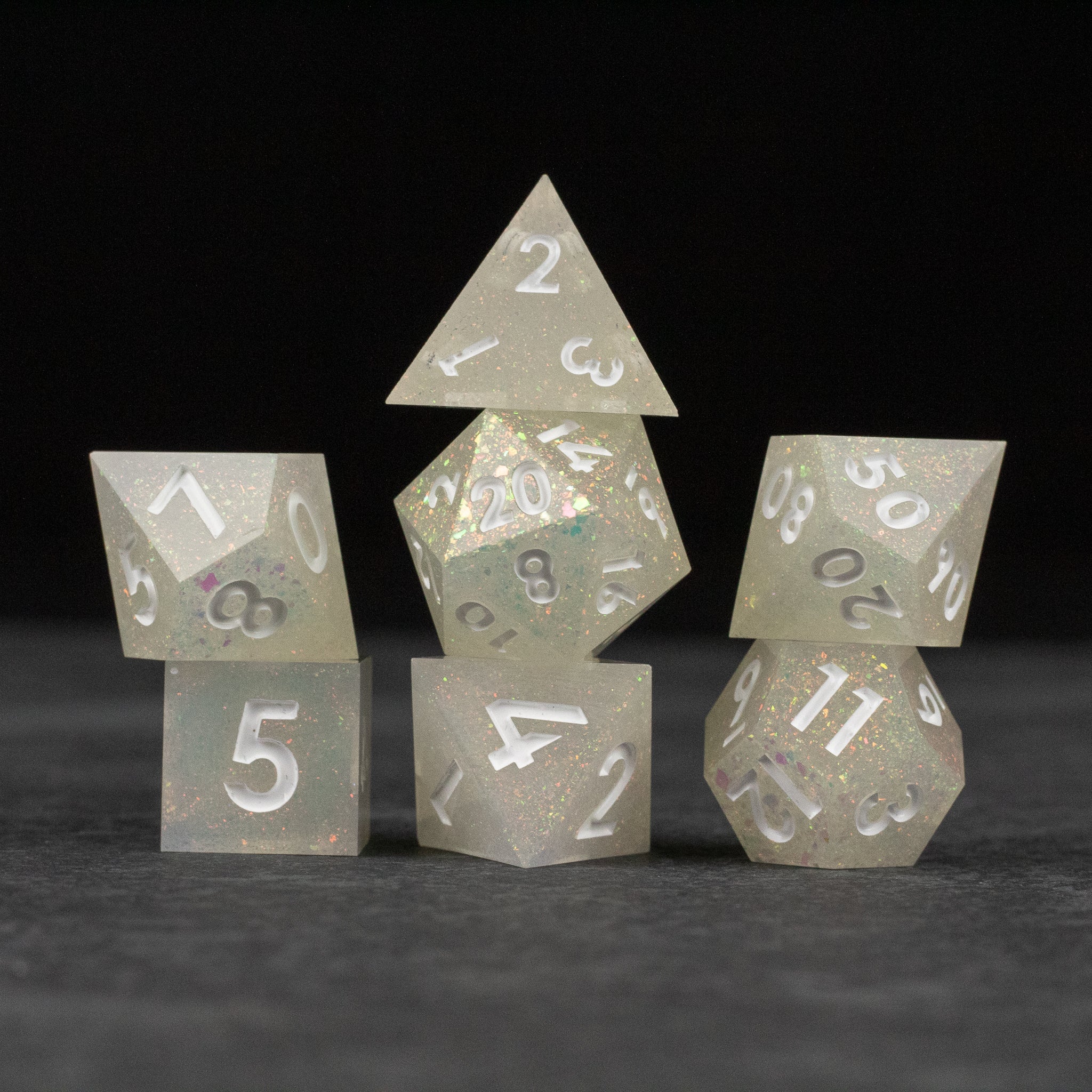 Snowfield Dice Set - Translucent white seven-piece dice set with sharp edges and silver numbers on a dark background.