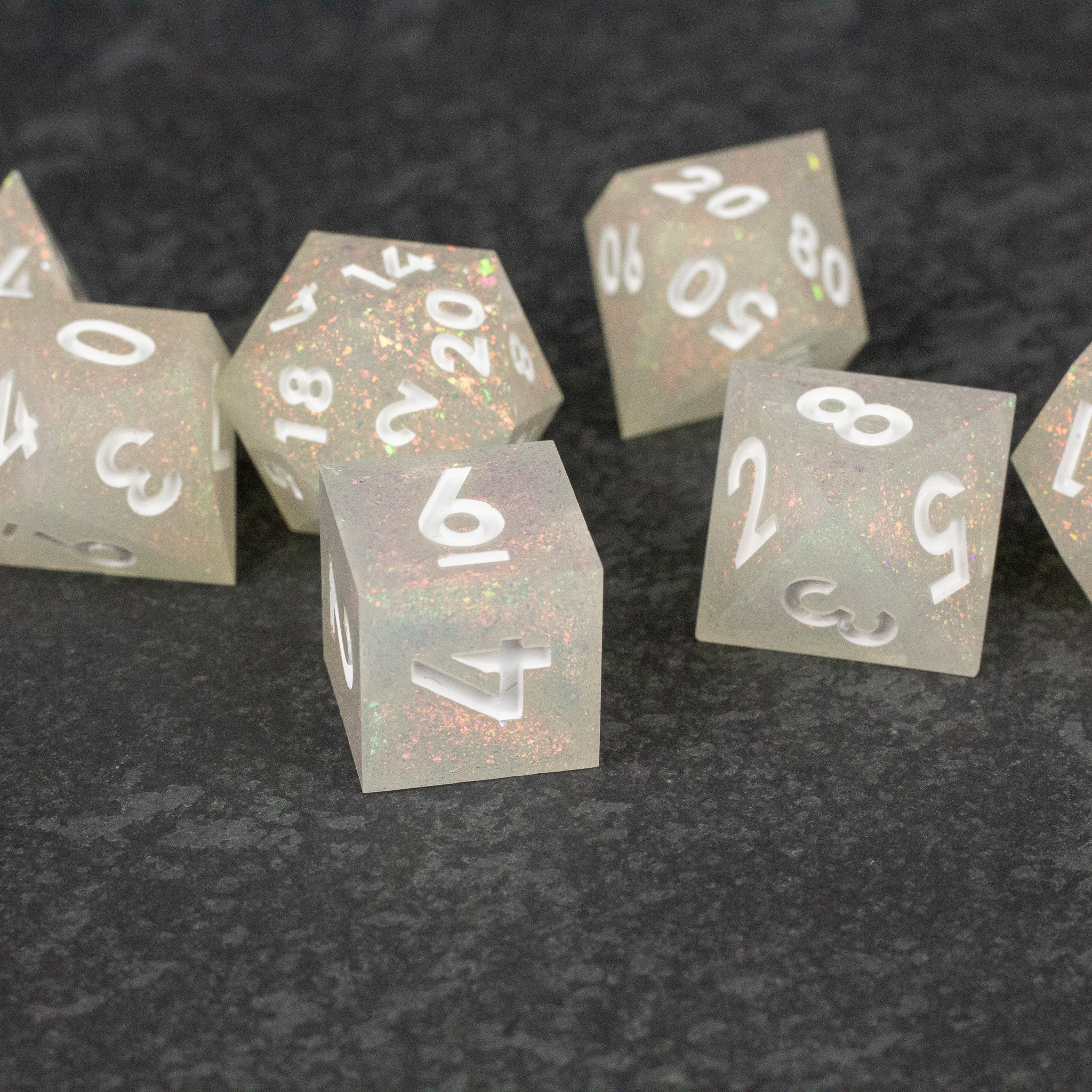 Snowfield Dice Set - Set of translucent white sharp-edged dice with white numbering and subtle glitter inside on dark surface.