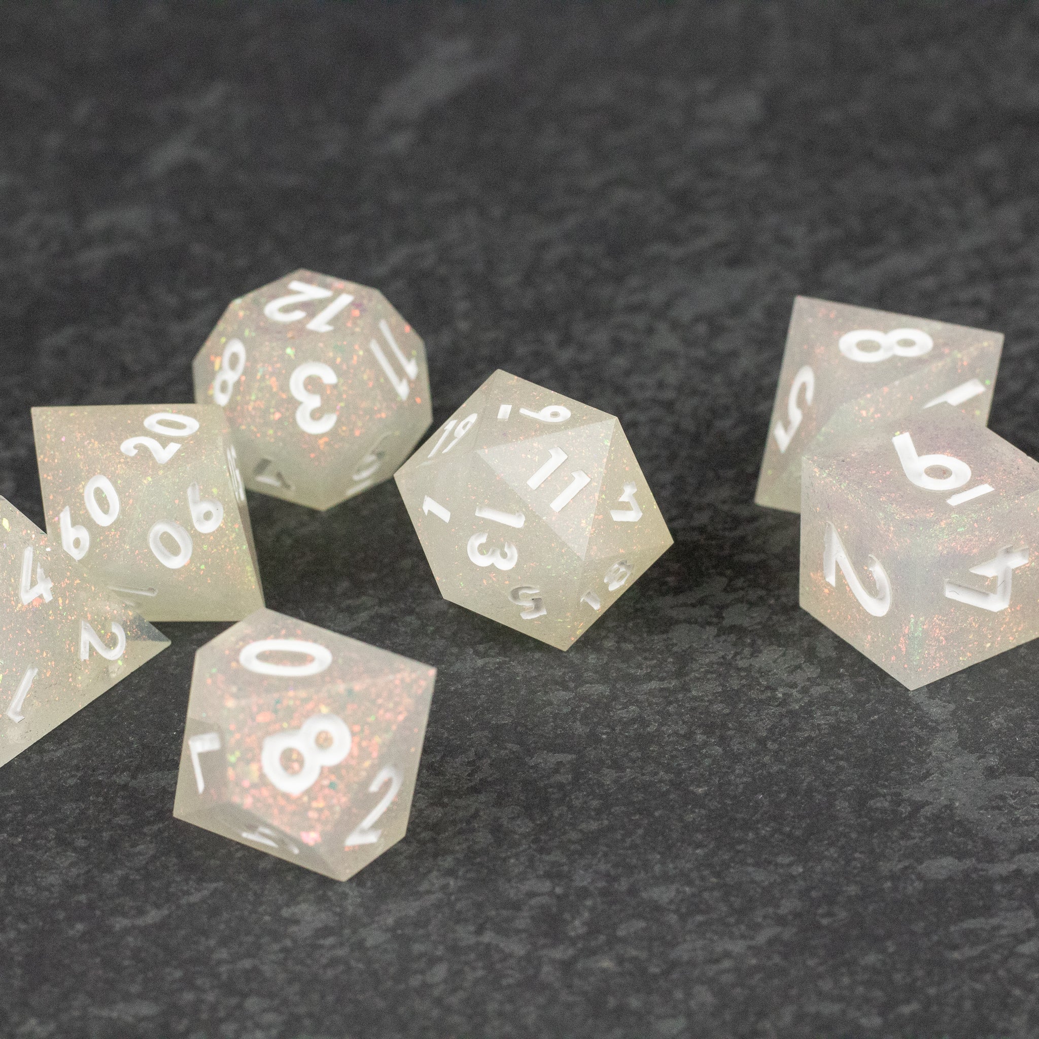 Snowfield Dice Set - Translucent white polyhedral dice set with sharp edges and clear white numbering on a dark surface.