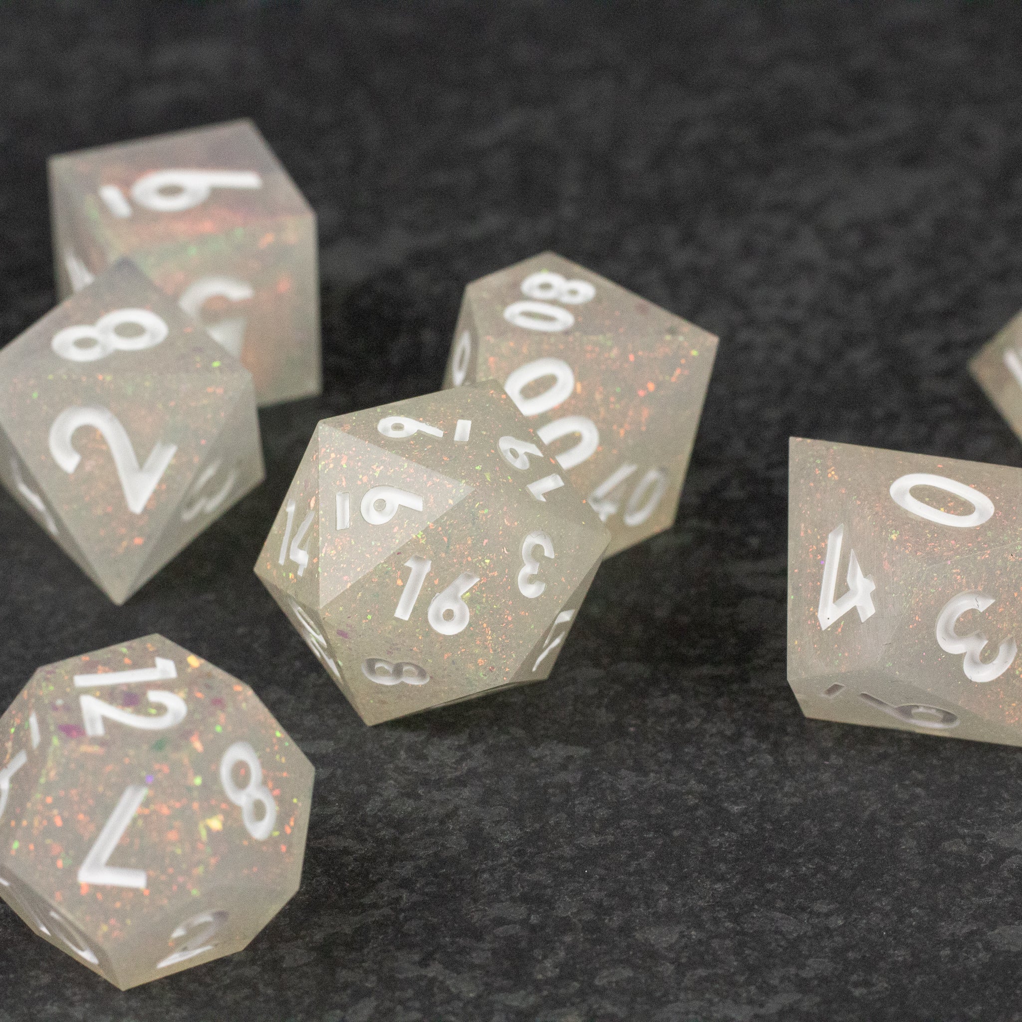 Snowfield Dice Set - Translucent white sharp-edged polyhedral dice set with silver numbers on black textured surface.