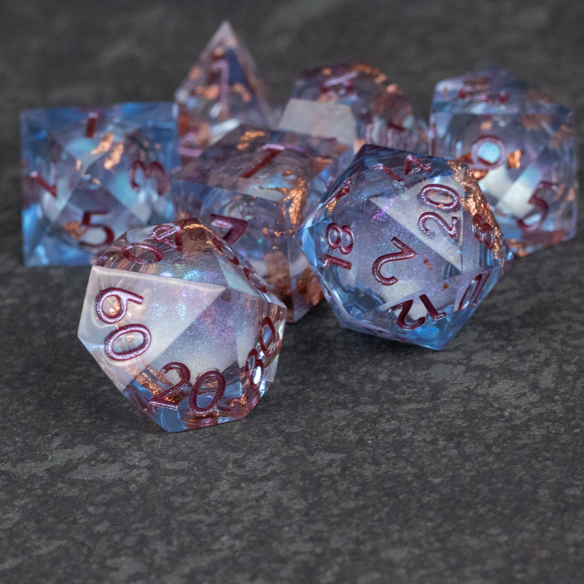 Temporal Rift Liquid Core Dice Set - Blue liquid core sharp edge polyhedral dice set with red numbering on dark surface.