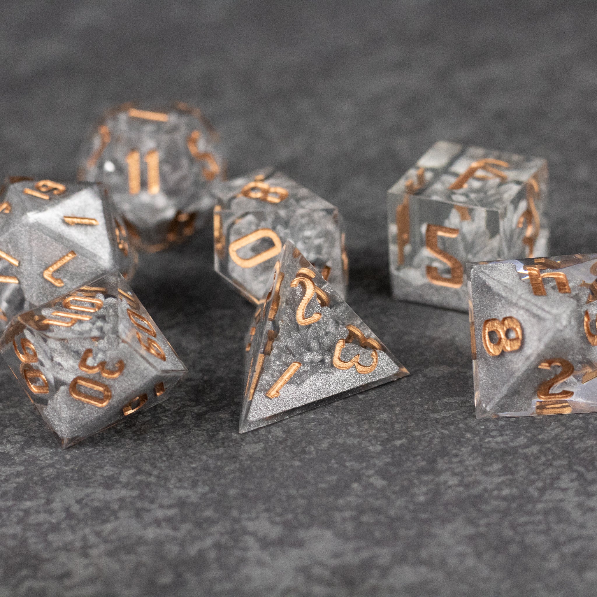 Silver Crystal Dice Set - Set of seven silver dice with sharp edges and metallic orange numbers on clear crystal material.