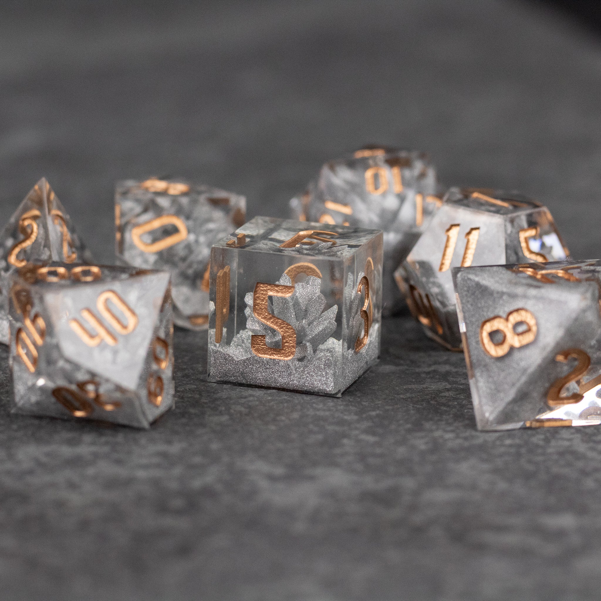 Silver Crystal Dice Set - Set of clear resin dice with sharp edges, silver flakes inside, and metallic gold numbering.