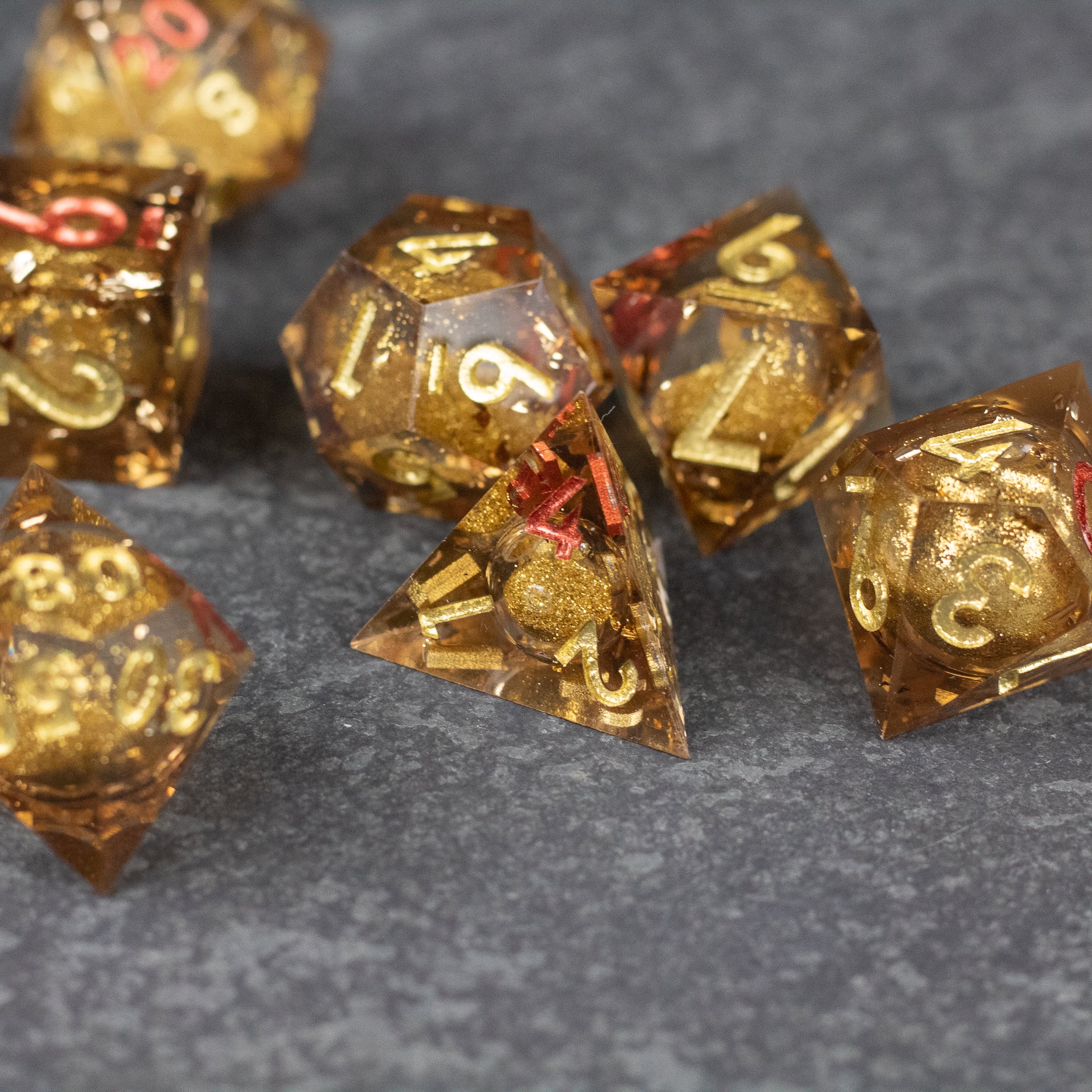 Dragon's Hoard Liquid Core Dice Set - Translucent golden liquid core polyhedral dice set with sharp edges and white numbering on a dark textured surface.