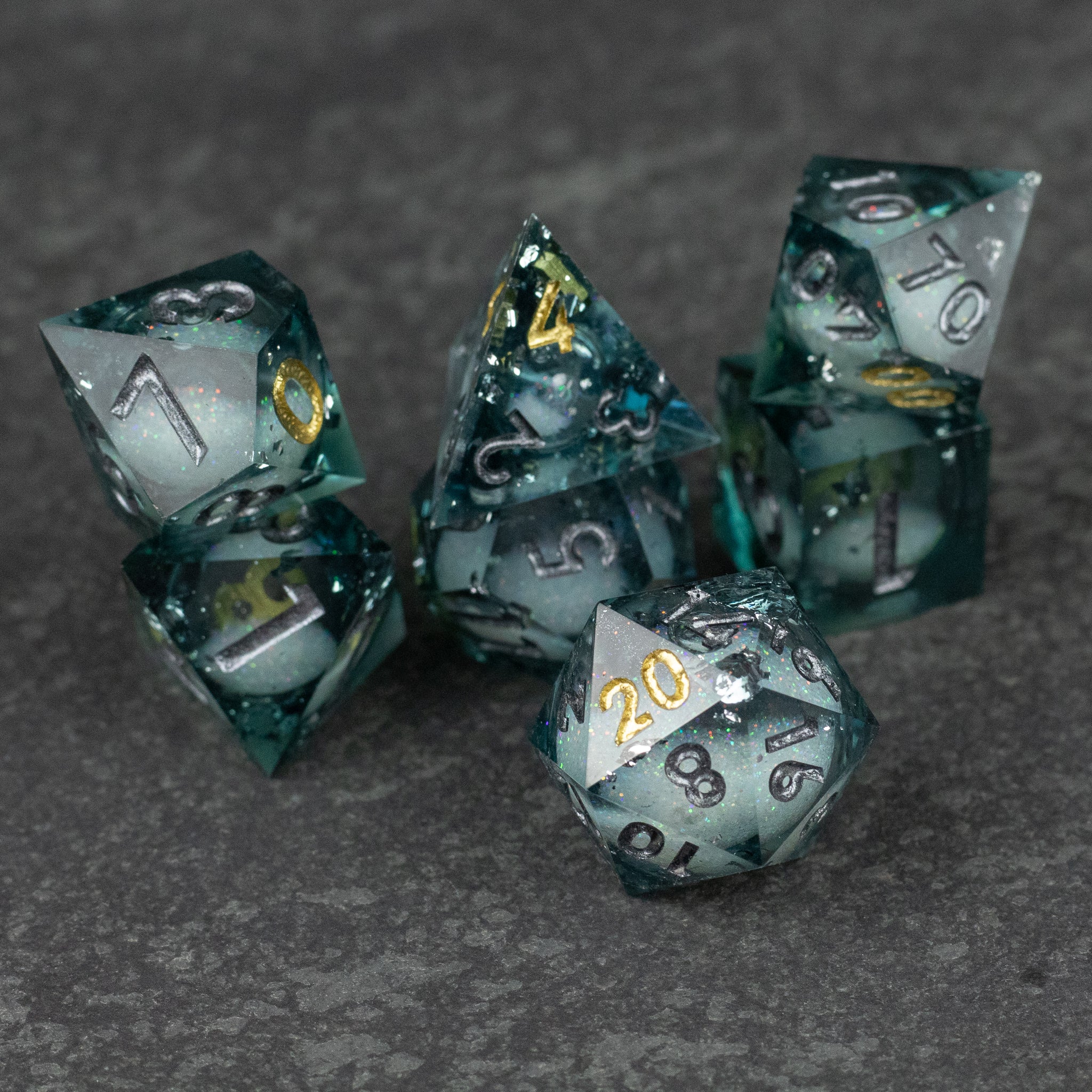 Call Of The Deep - Liquid Core Dice Set - Translucent teal sharp-edged dice set with silver numbering and liquid core effects.