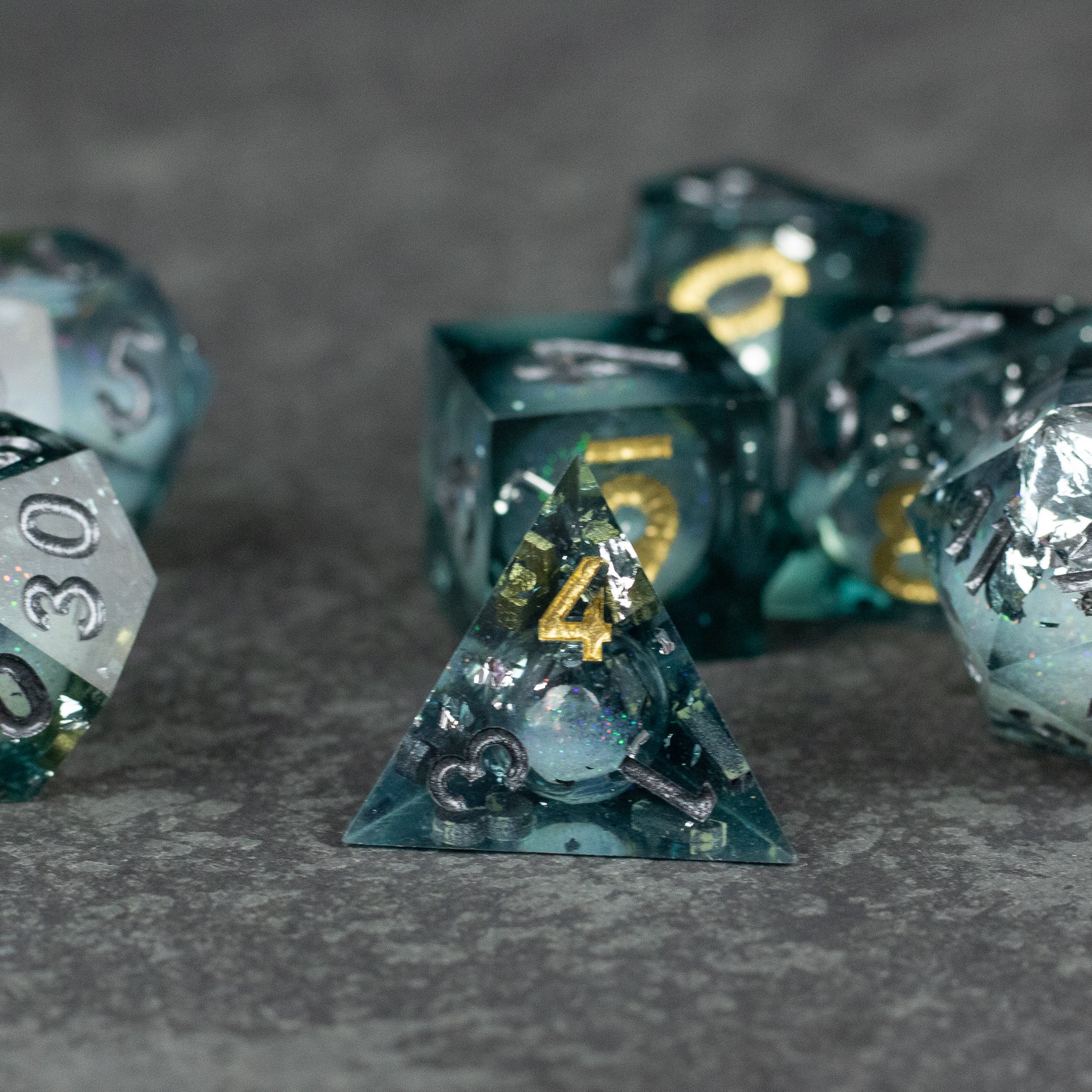 Call Of The Deep - Liquid Core Dice Set - Translucent green liquid core sharp-edged polyhedral dice with gold numbering, including d4, d6, d20.