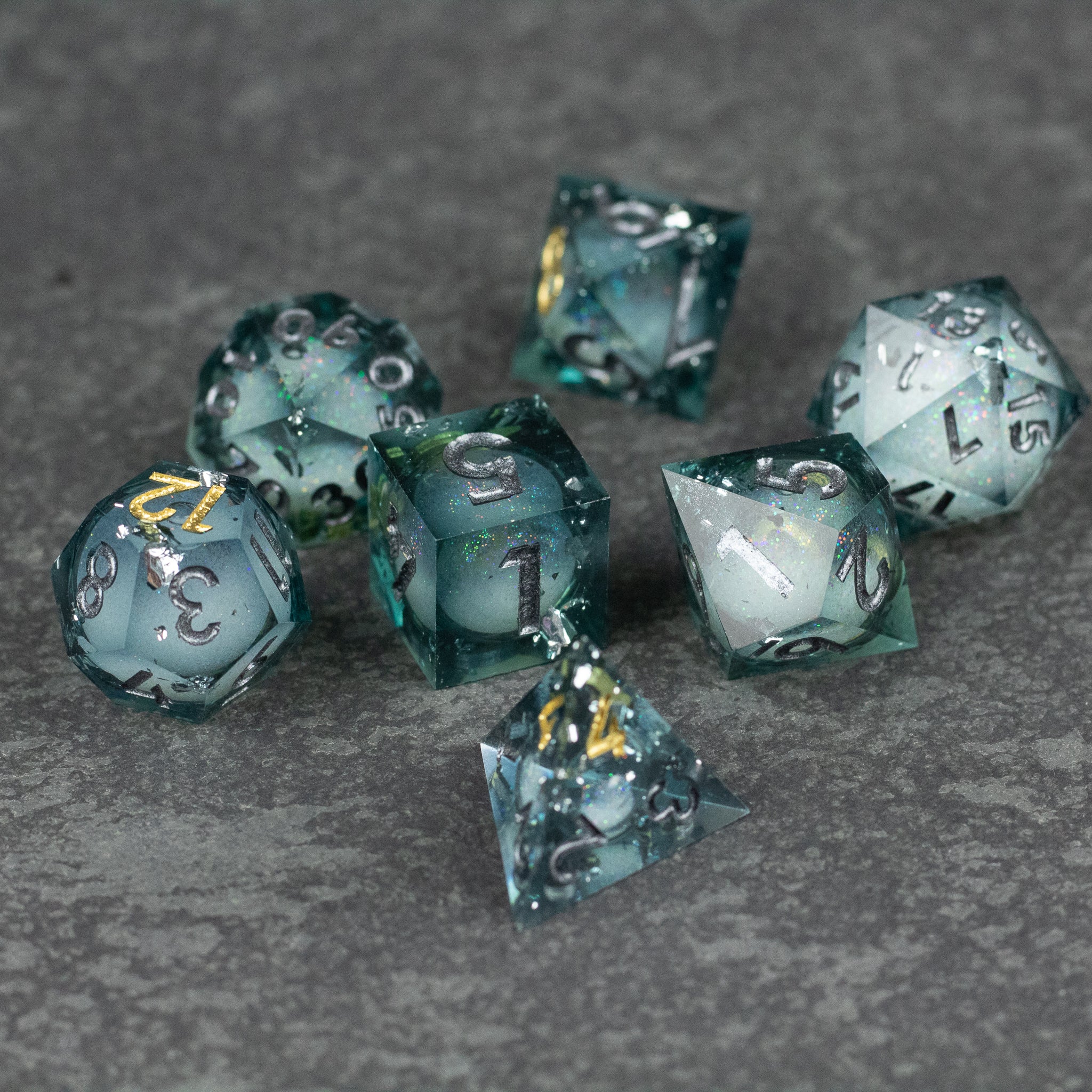 Call Of The Deep - Liquid Core Dice Set - Set of seven sharp-edged polyhedral dice with translucent blue-green liquid core and silver numbers.