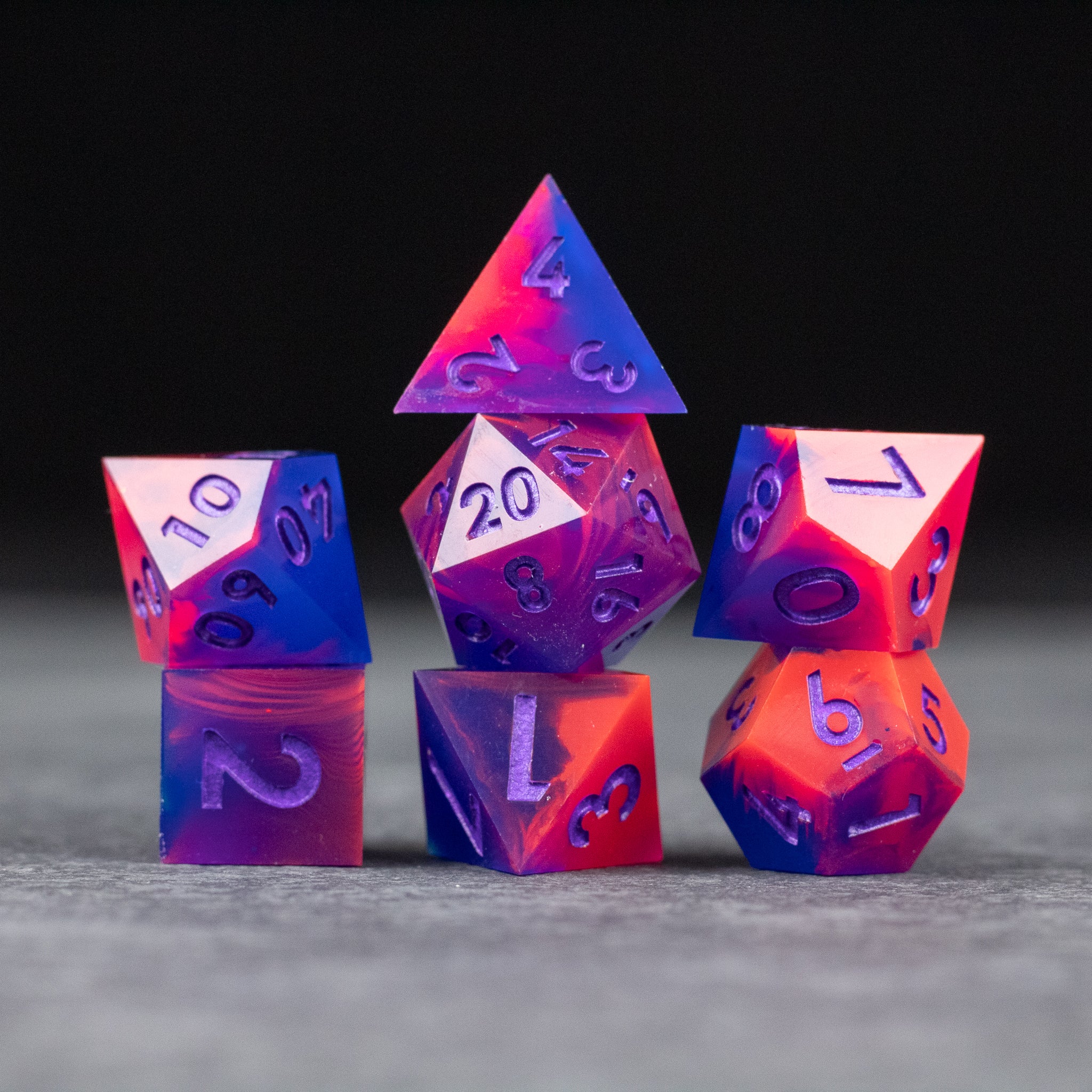 Outrun Dice Set - Set of seven sharp-edged purple and orange neon polyhedral dice with white numbering on a gray surface.