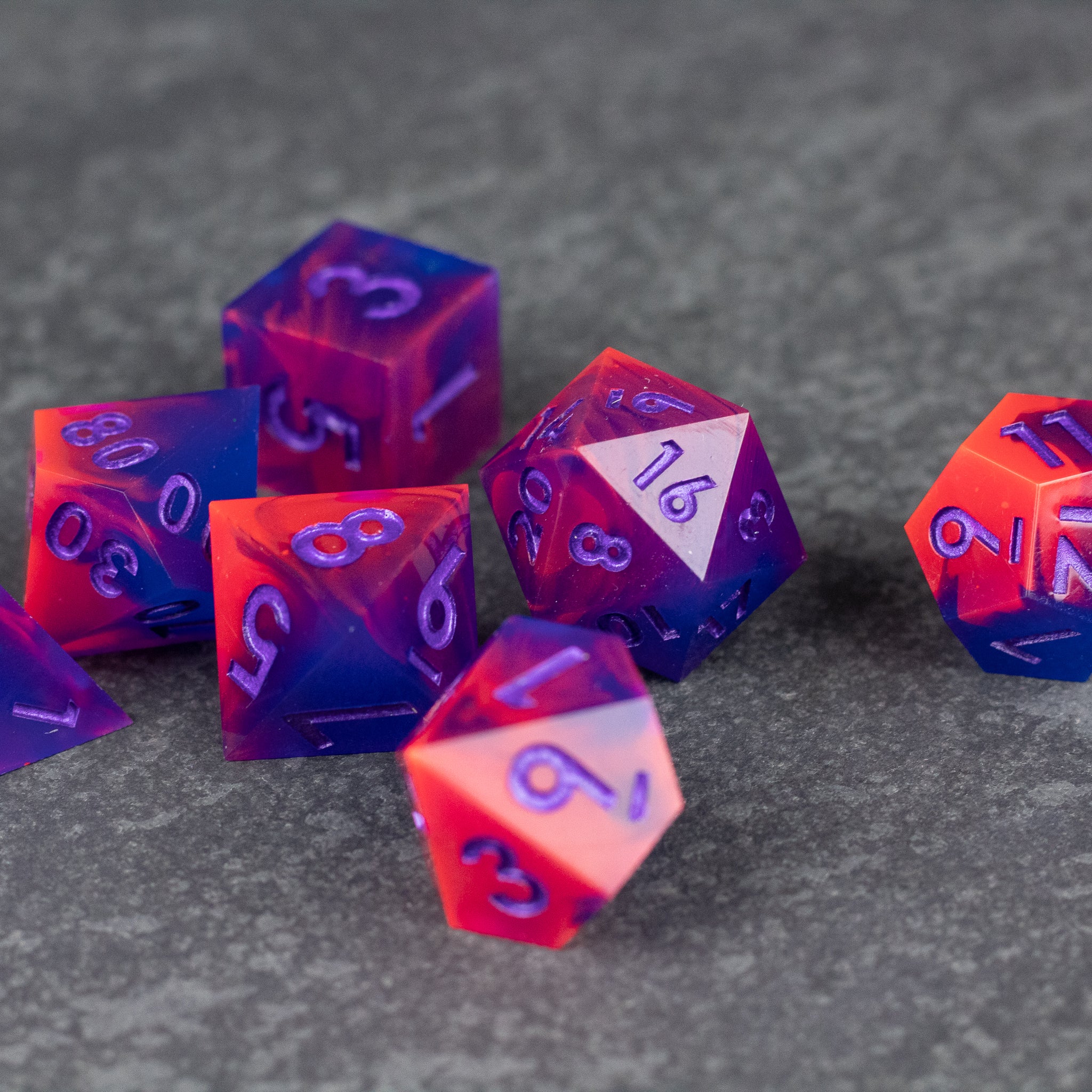 Outrun Dice Set - Sharp-edged polyhedral dice set in neon purple and orange with pink numbers on a dark textured surface.