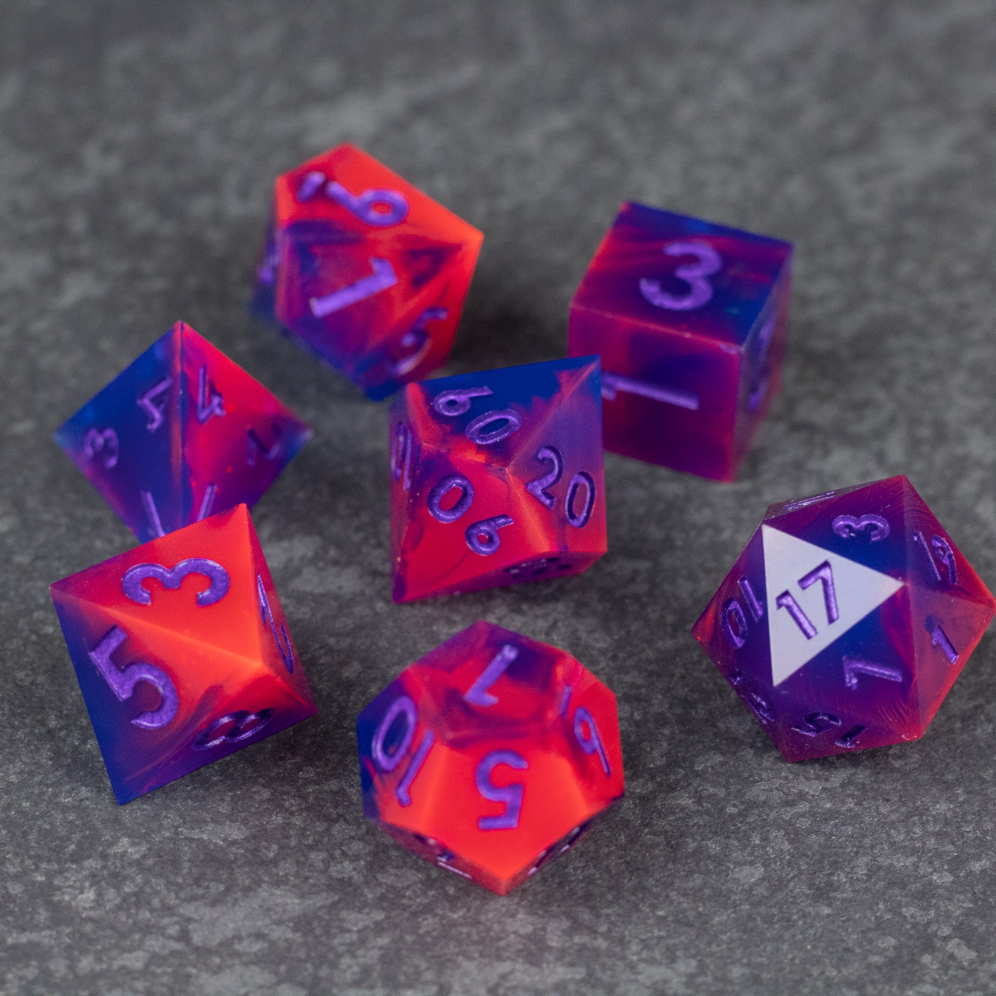 Outrun Dice Set - Seven sharp-edged polyhedral dice in neon orange and purple with contrasting numbers on a dark textured surface.