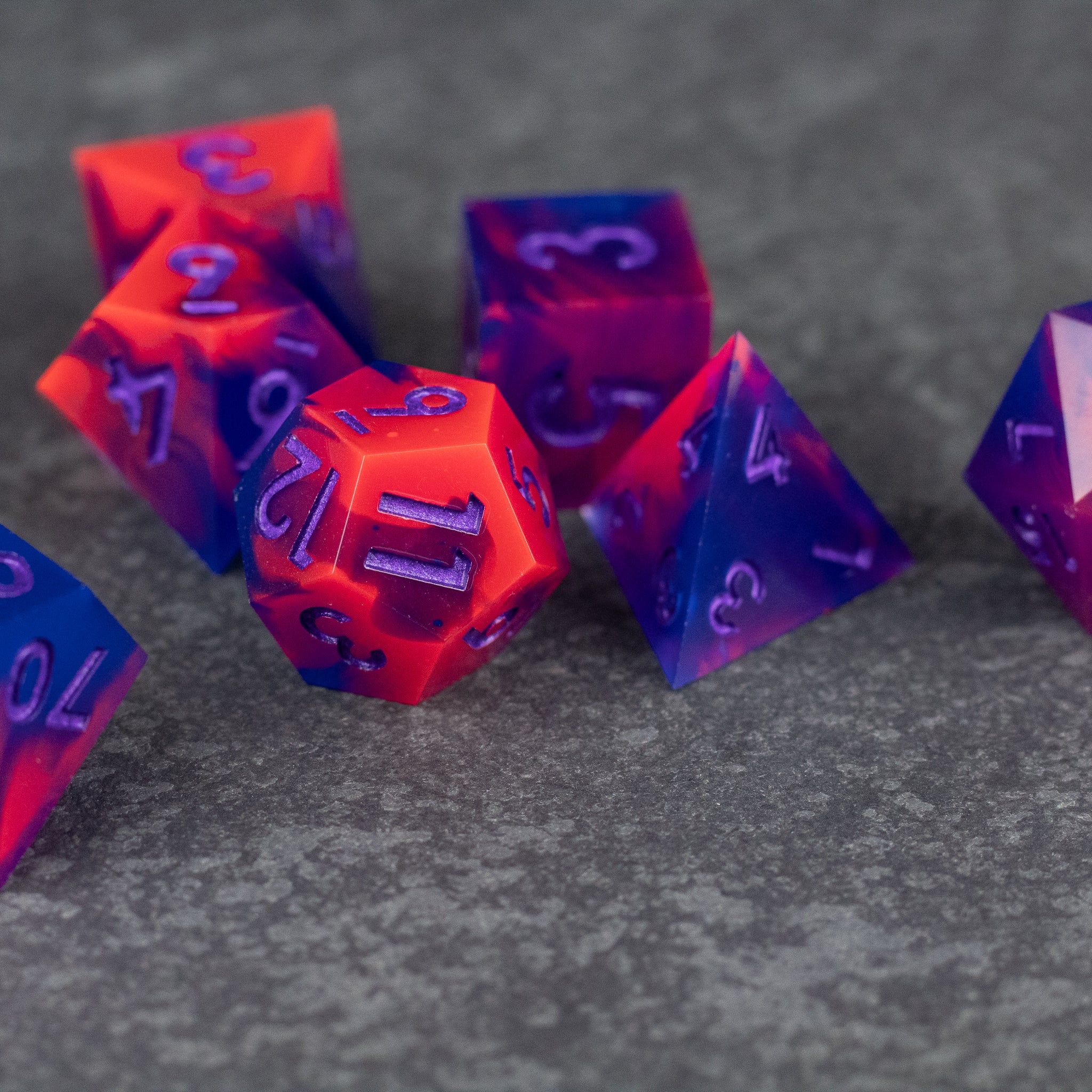 Outrun Dice Set - Set of sharp-edged polyhedral dice in vibrant neon orange and purple with contrasting number engravings.