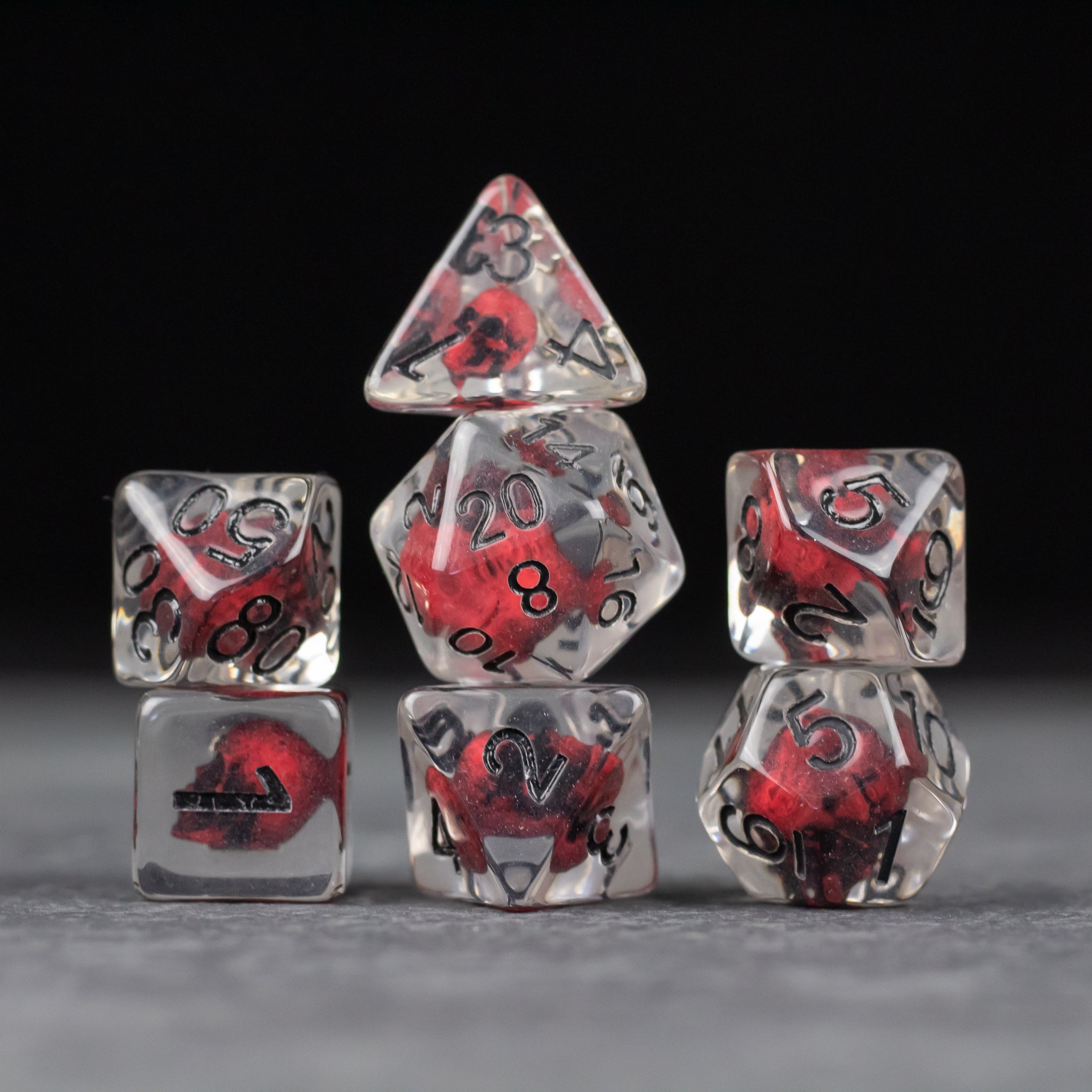 Red Skull Dice Set - Clear polyhedral dice set with red skull inclusions and black numbers on each face.