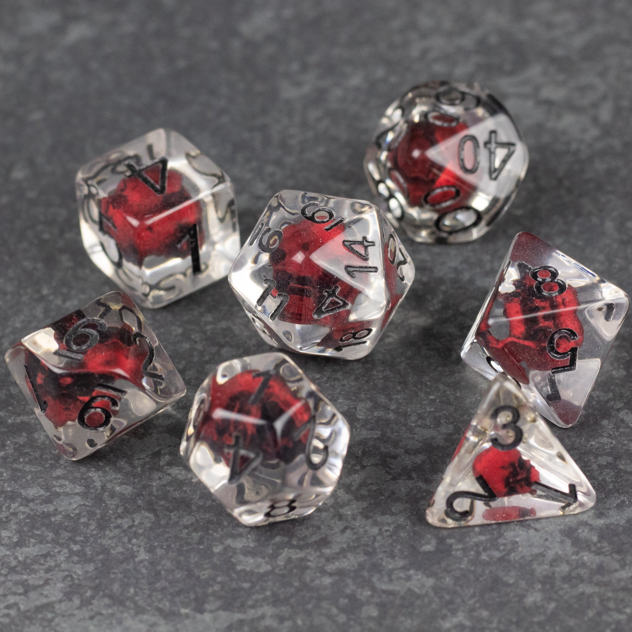 Red Skull Dice Set - Transparent polyhedral dice set with red skulls inside and black numbering.
