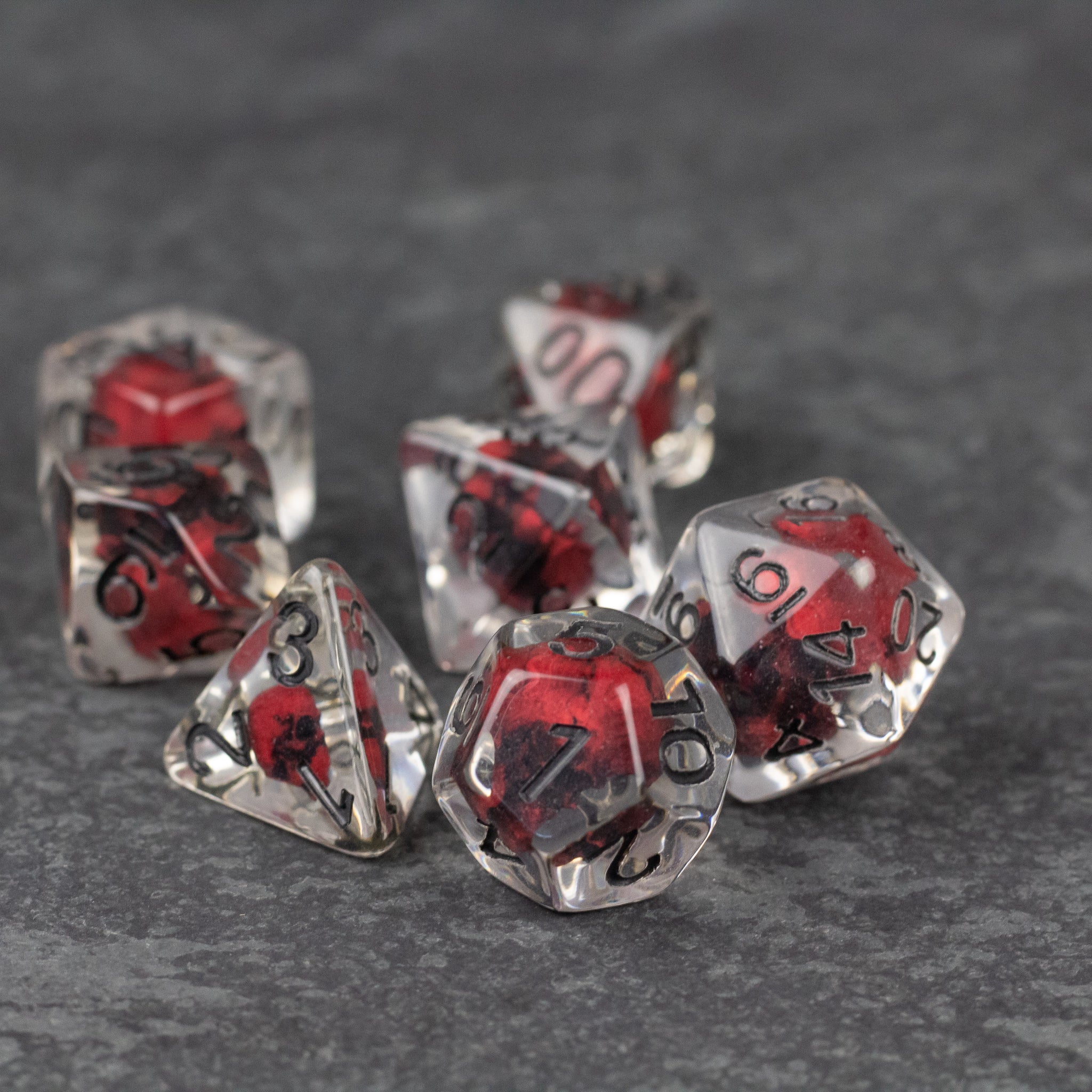 Red Skull Dice Set - Set of seven transparent dice with red skull designs inside and black numbering on each face.