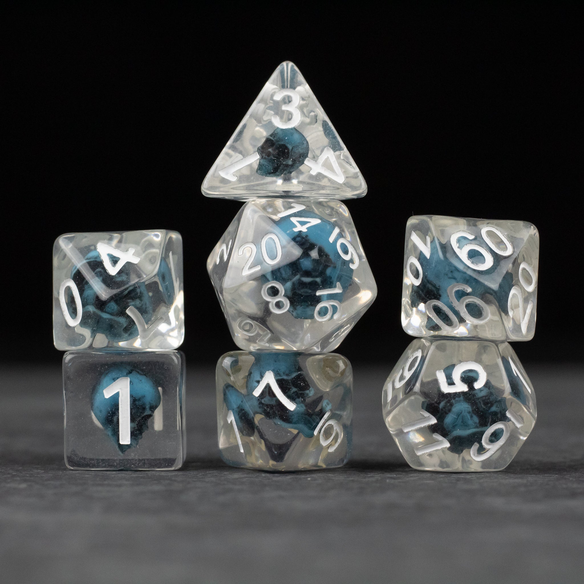 Blue Skull Dice Set - Set of seven transparent dice with blue skulls inside and white numbering on a dark background.