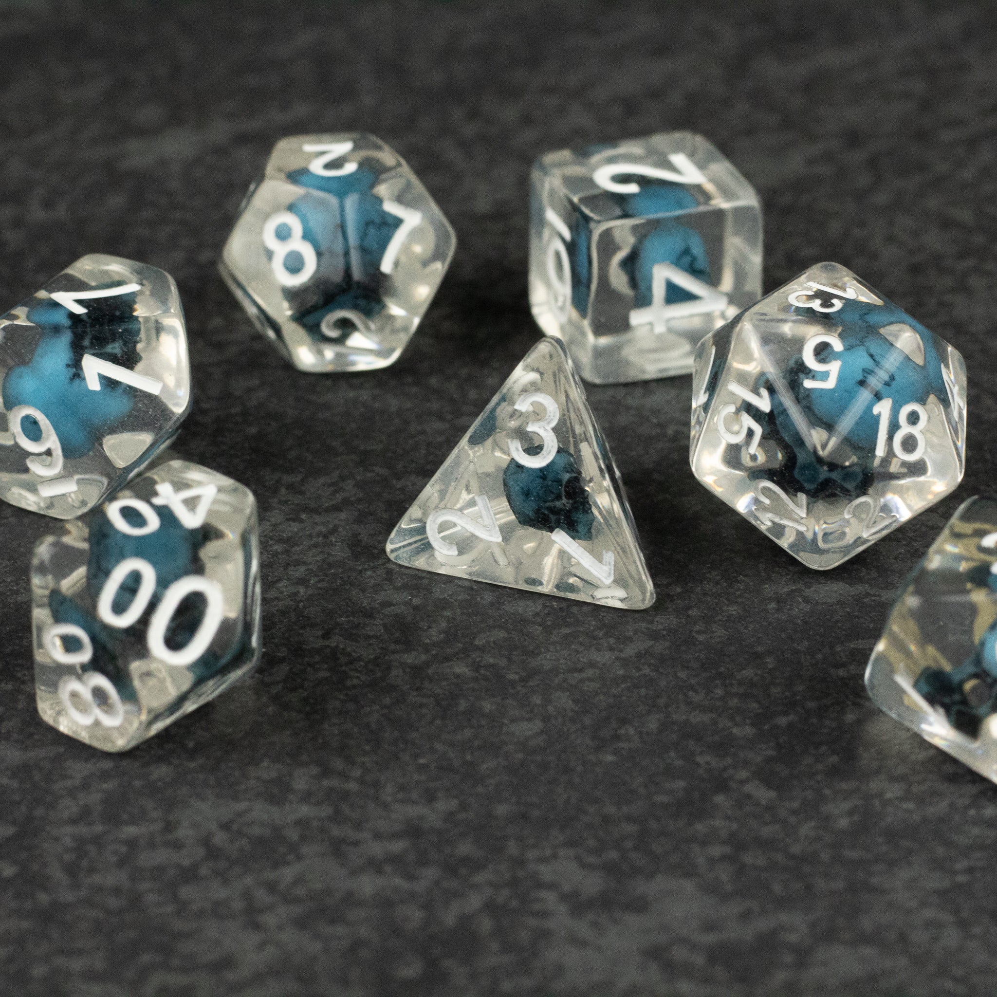 Blue Skull Dice Set - Set of translucent dice with blue skulls inside, white numbering, various polyhedral shapes.