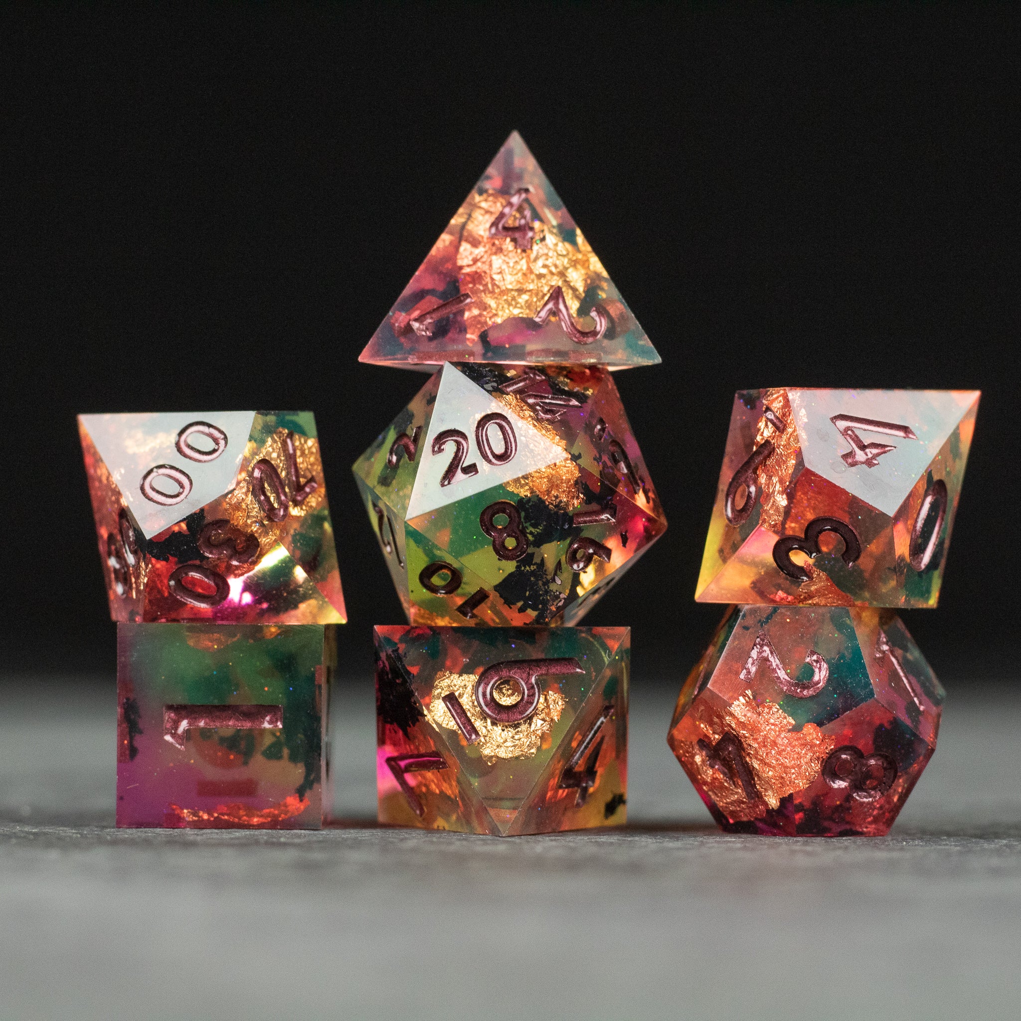 Dawn Ritual Dice Set - Set of six translucent sharp-edged dice with gold numbers and embedded gold flakes in red and green hues.