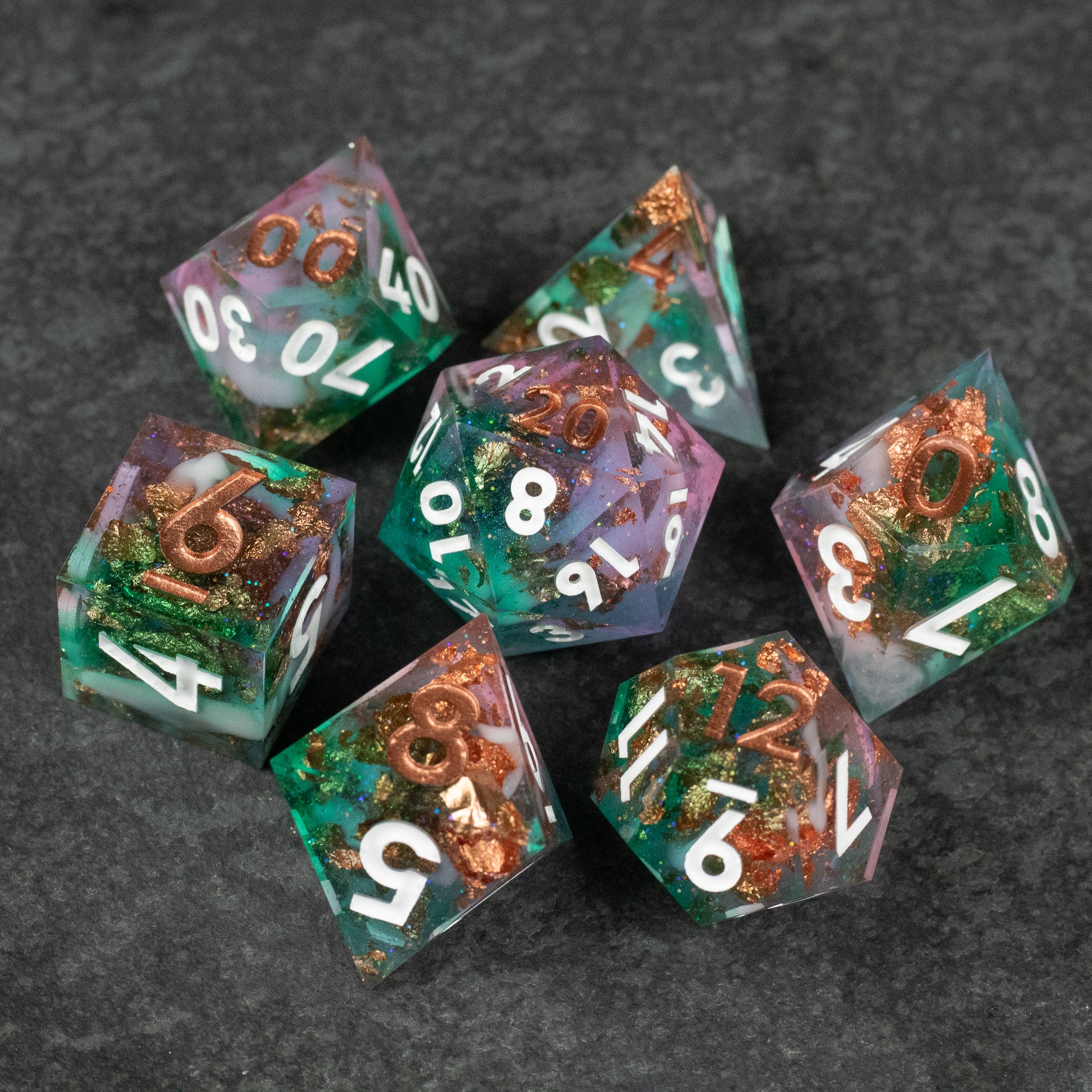 Scapeshift Dice Set - Seven-piece polyhedral dice set with translucent green and copper inclusions, white numbers, sharp edges.